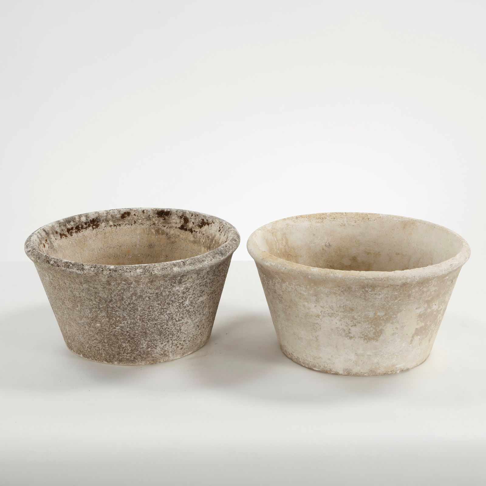 Pair of Tapered Round Concrete Planters, 1960s: Tapered round concrete planters with understated profiles and mineral coloration, offering a timeless garden form marked by natural wear. Height: 8 in. Diameter: 15.5 in.