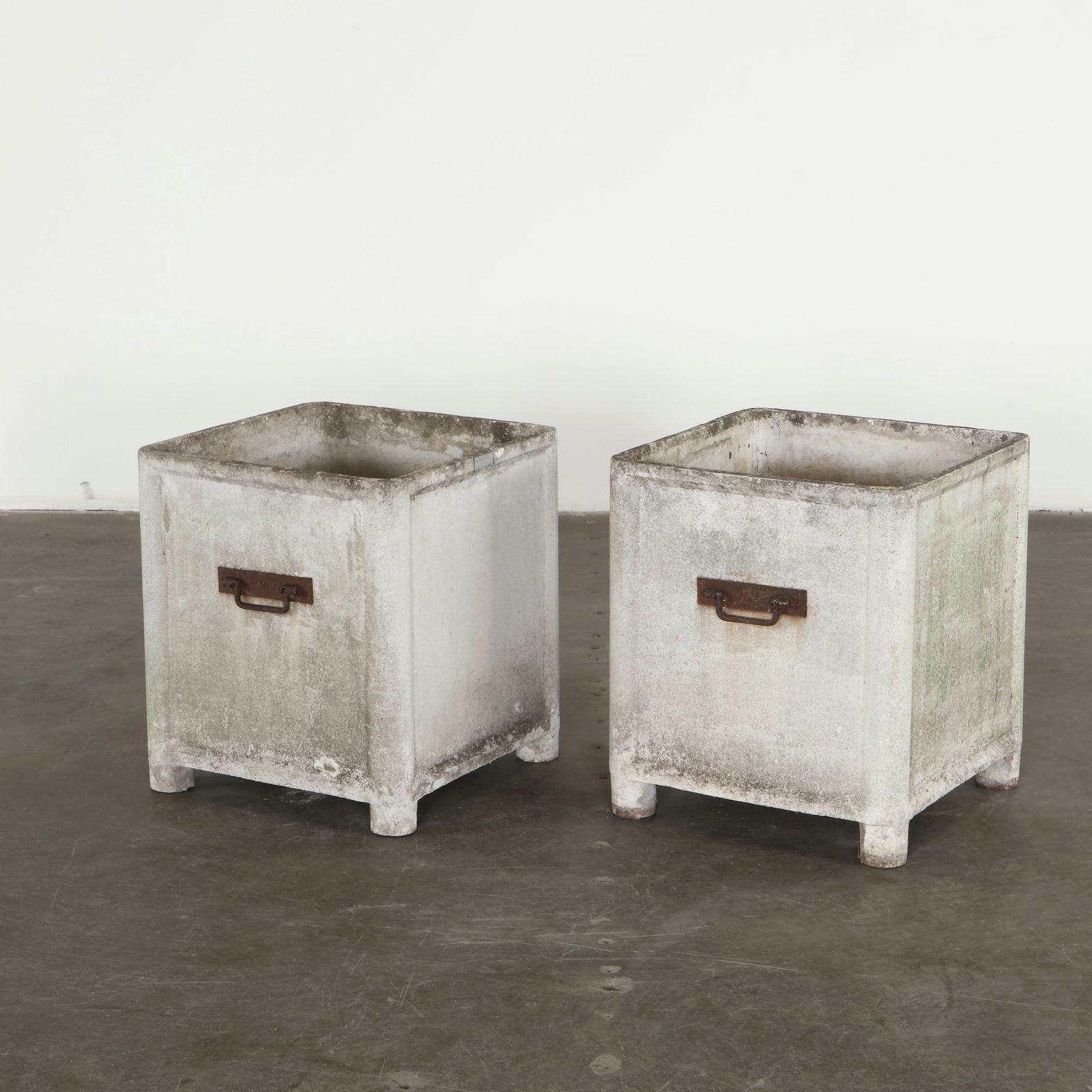 Willy Guhl , Pair of Medium Square Planters with Metal Handles, 1960s: Crafted in textured composite with the restrained geometry typical of Willy Guhl, this pair of medium square planters presents subtly tapered proportions resting on rounded feet. The surfaces show a