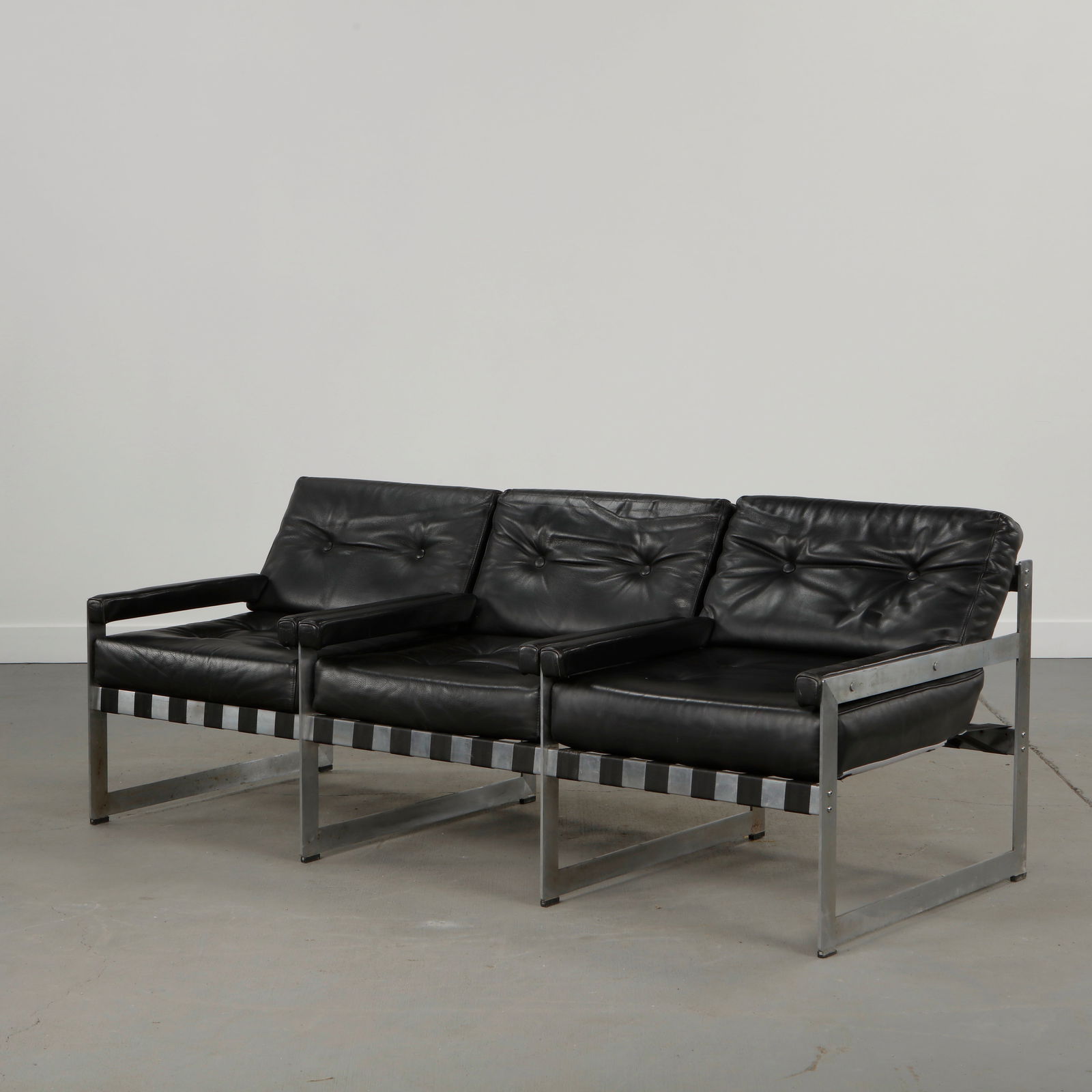 Mid-Century Black Leather Sofa with Metal Frame, 1970s: Sculptural sofa upholstered in black leather, resting on a chromed metal frame, combining comfort with clean modernist lines. Height: 29 in. Width: 73 in. Depth: 31.5 in. Seat Depth: 19 in. Seat Heigh