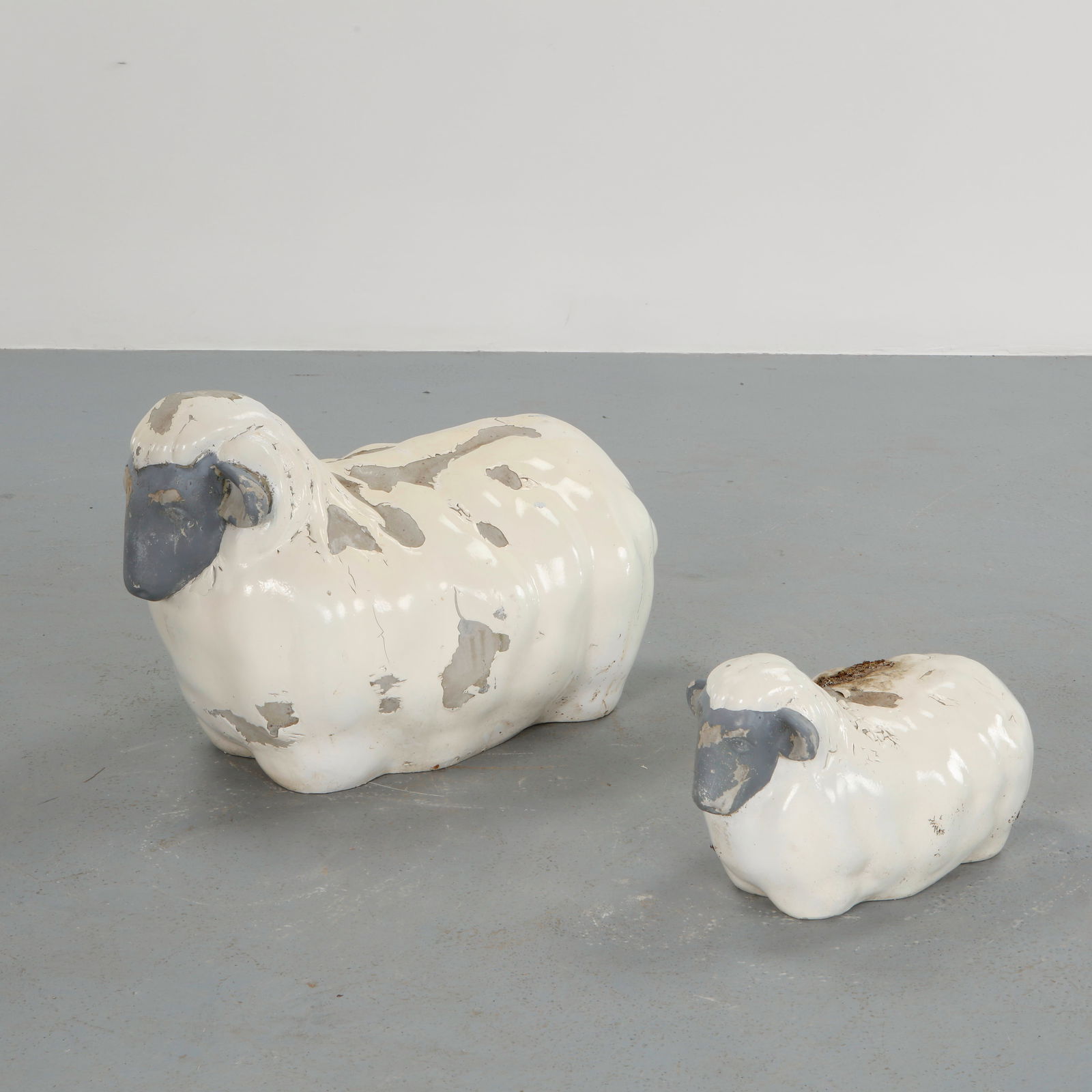 Pair of Sheep Concrete Sculptures, 1960s: Modeled in concrete with a weathered painted surface, this charming pair of sheep sculptures captures the pastoral spirit of mid-century garden ornamentation. Their sculptural presence and aged