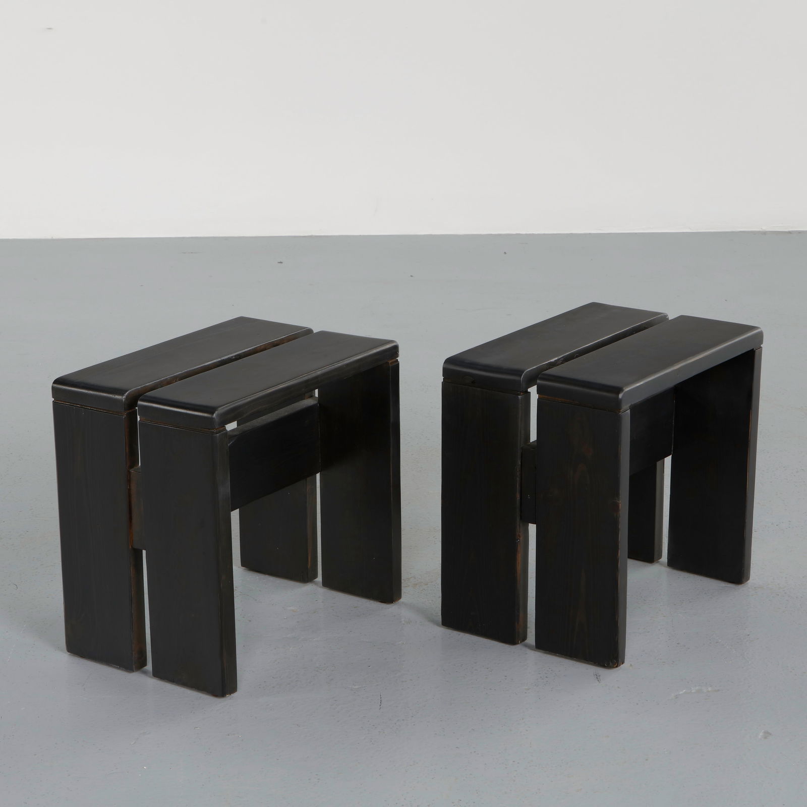 Charlotte Perriand for Les Arcs 1600, Pair of Black Pine Stools, 1960s: Crafted in stained pine, this pair of stools reflects the rigorous alpine vocabulary developed for Les Arcs. Their architectural construction and compact proportions embody Perriand functional approac