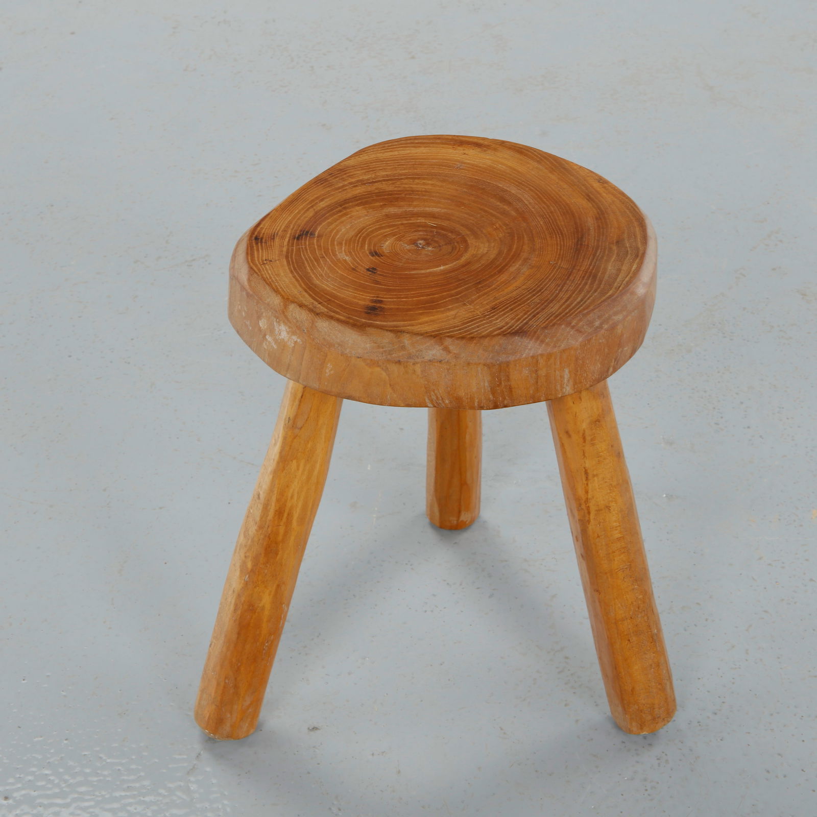 Brutalist Wood Stool, 1960s: Carved from a solid section of wood, this stool features a thick circular seat revealing concentric growth rings, supported by three robust legs. The expressive grain and honest construction celebrate