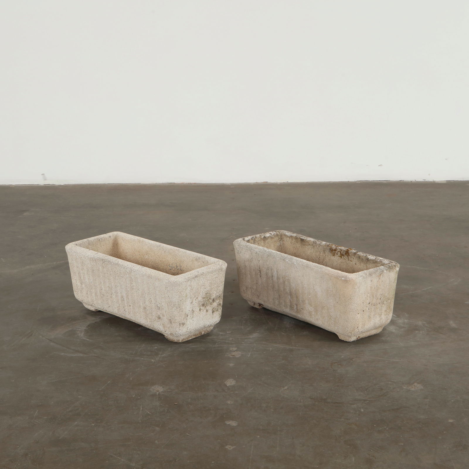 Pair of Rectangular Limestone Planters, 1960s: Carved in solid limestone with a clean rectangular profile, this pair reveals the gentle weathering and moss traces characteristic of long outdoor use. Their substantial weight and quiet texture lend