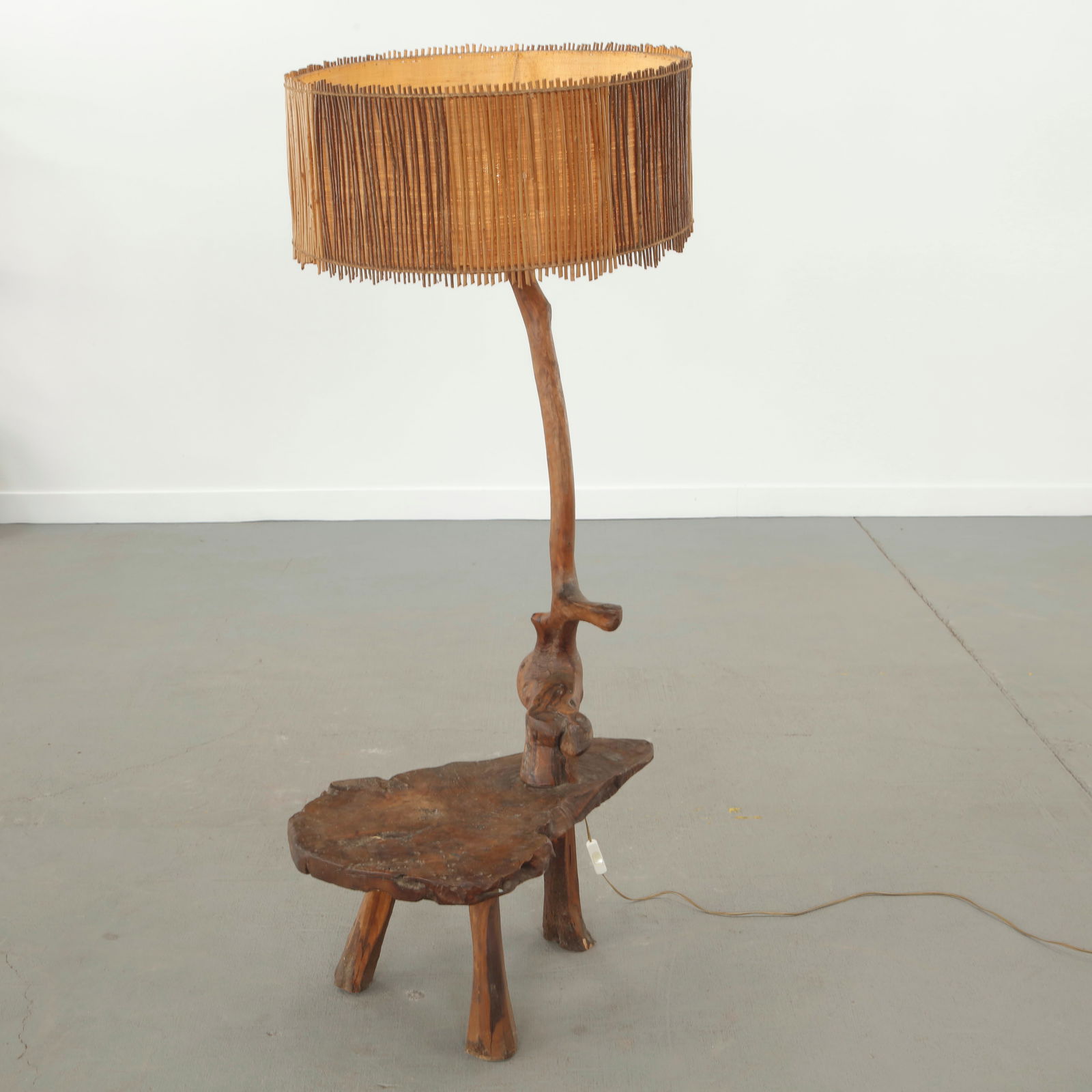 Carved Rootwood Lamp Side Table, France, 1960s: Sculptural floor lamp carved from a single piece of solid rootwood, featuring an integrated low table and an organically bent stem. Executed with a slatted natural fiber shade, the piece embodies a