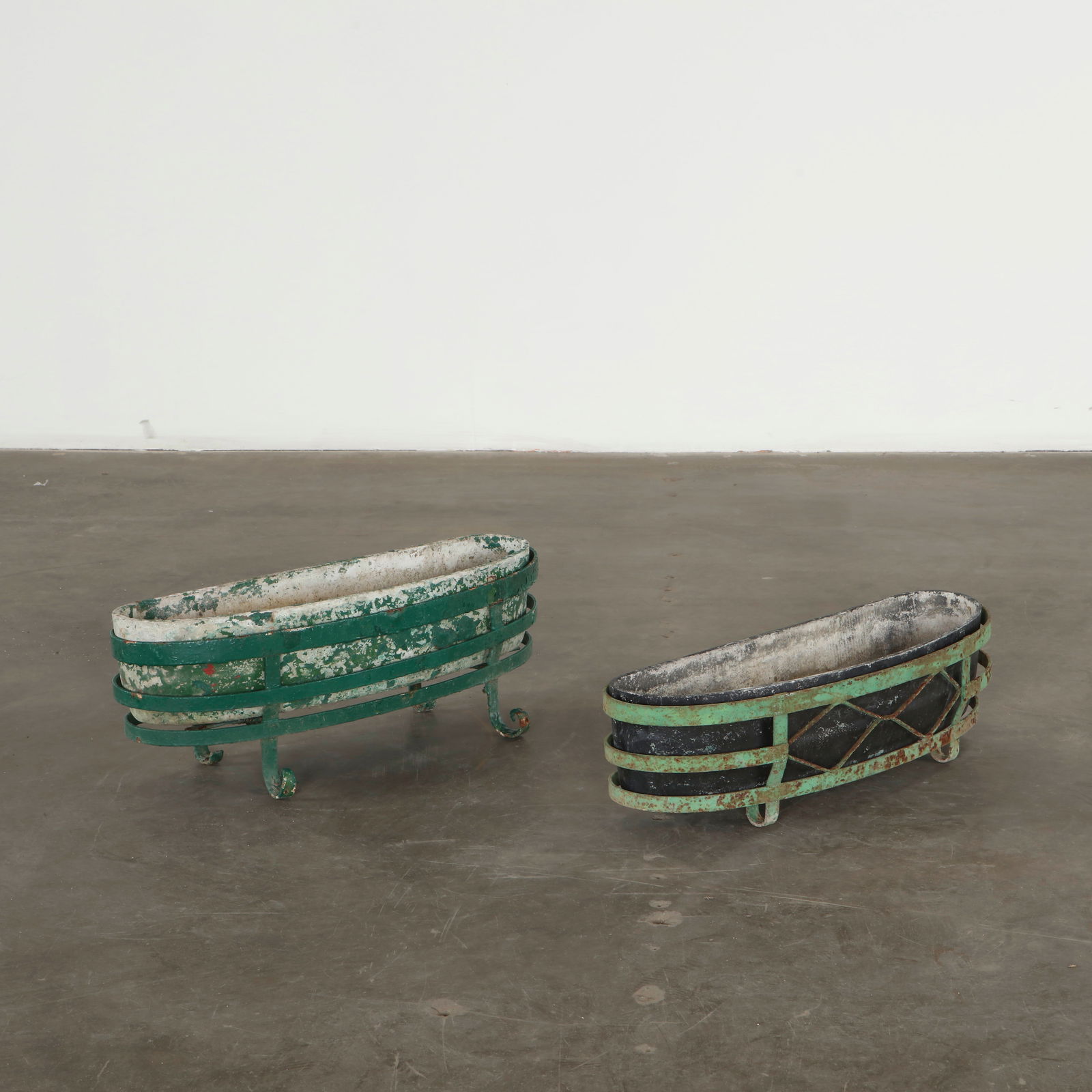 Pair of Concrete Planters on Stands, 1960s: Each planter is executed in cast concrete resting within a wrought iron stand, retaining layers of historic paint and richly weathered surfaces. The patina of oxidation, flaking pigment and