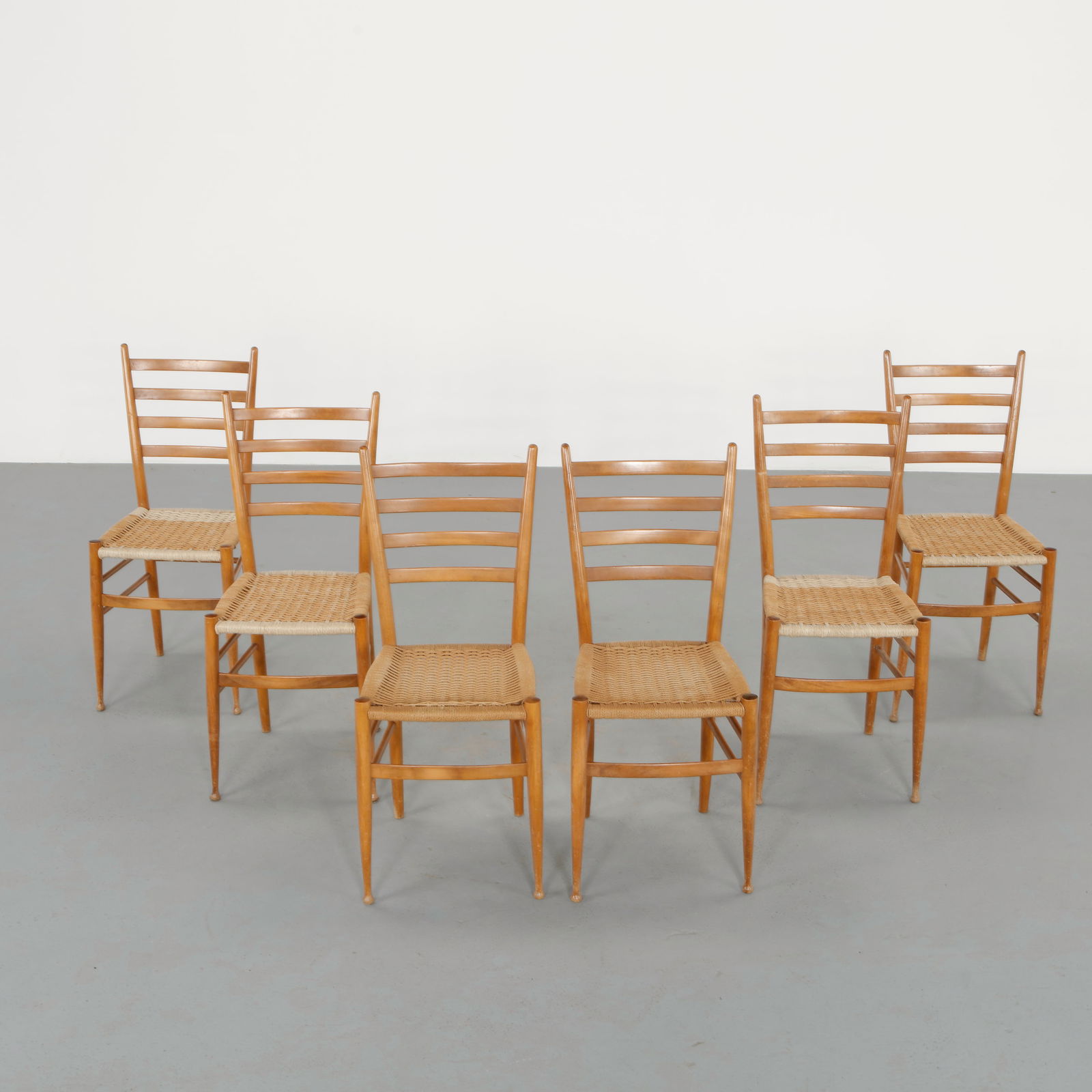 Set of Six Ladder Back Chairs attributed to Gio Ponti, 1960s: Constructed in light toned wood with slender tapered legs and distinctive ladder backrests composed of delicate horizontal slats. The woven rush seats provide warmth and tactile contrast to the refine