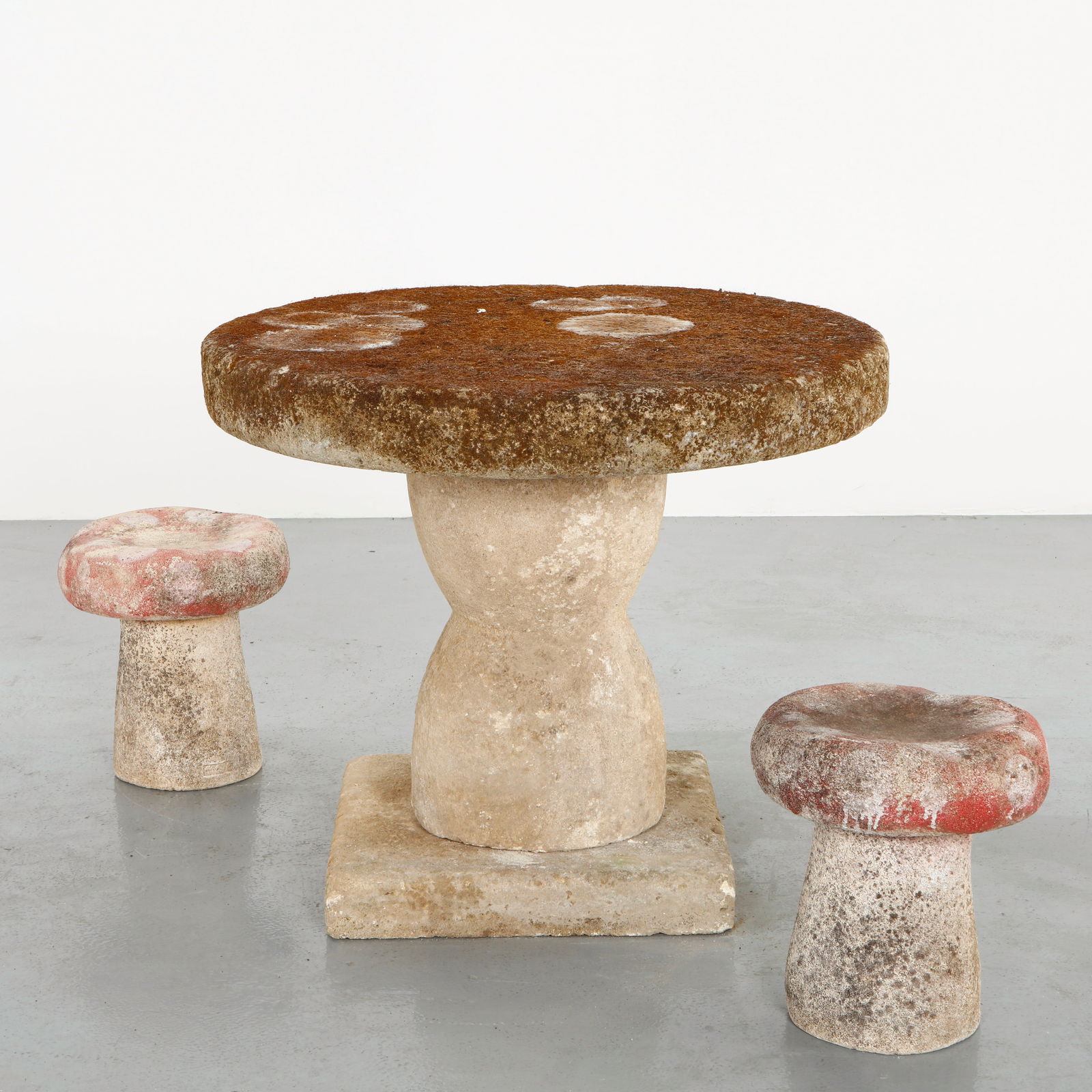 Mushroom Form Garden Set Stone and Concrete, 1960s: Featuring a circular table carved in stone accompanied by two sculptural mushroom form stools executed in concrete, this garden set presents a striking contrast of materials. The weathered surfaces an