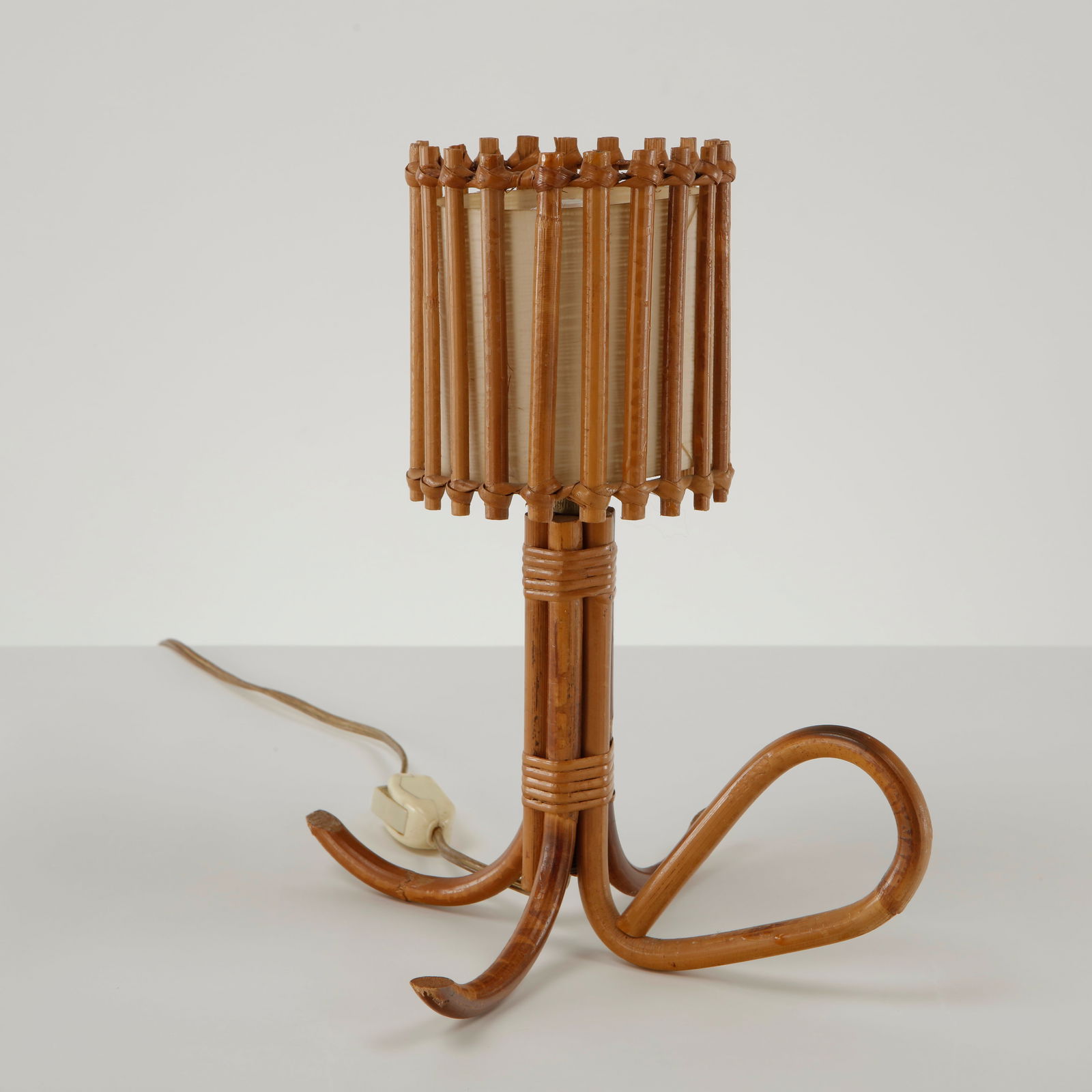Louis Sognot, Bamboo Table Lamp, France, 1950s: Executed in bamboo with a cylindrical parchment diffuser framed by vertical bamboo elements forming an open architectural shade. The sculptural base composed of flowing bent bamboo creates an elegant