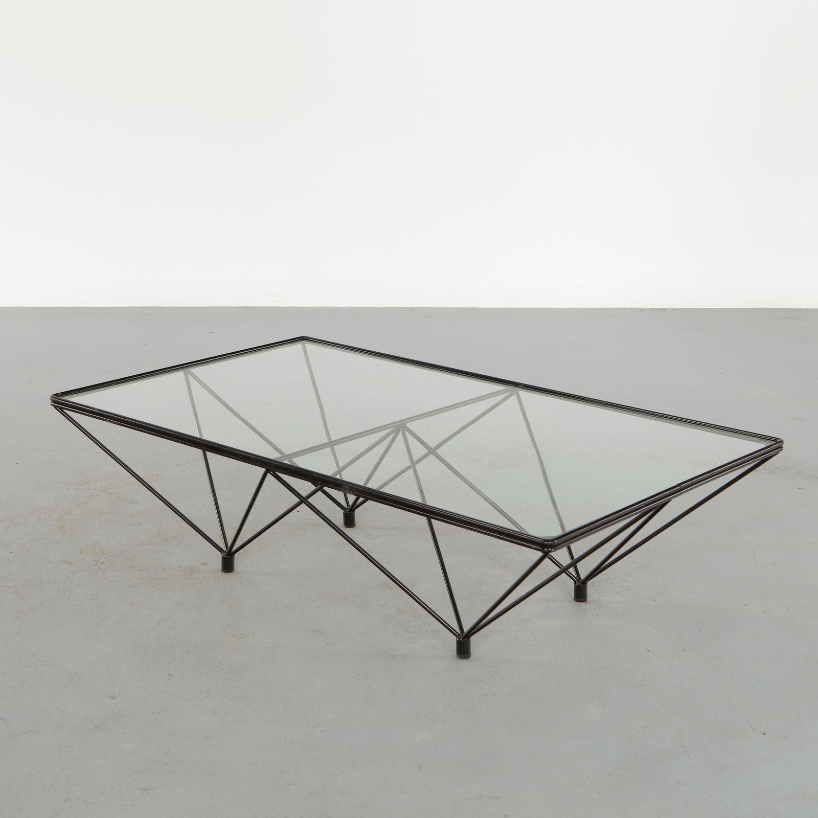 B&B Italia, Alanda Coffee Table, 1980s: Featuring a geometric steel wire base composed of intersecting triangular forms, the table supports a clear glass top revealing the architectural structure beneath. Designed with sculptural precision,