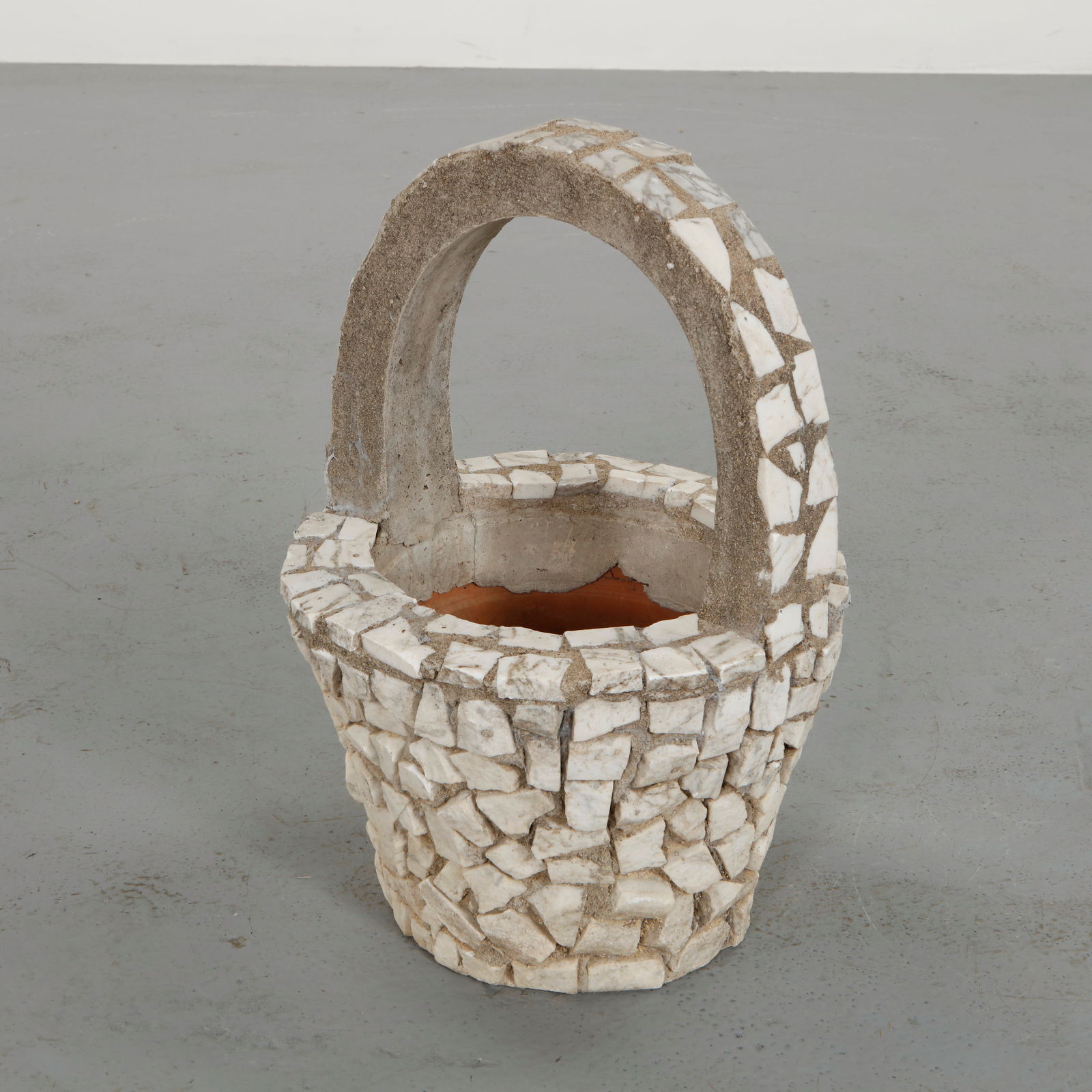 Mosaic Basket Planter, 1960s: Decorative planter executed in concrete and covered with irregular stone mosaic fragments. The arched handle and textured surface evoke a rustic sculptural character. A charming mid-century garden ele