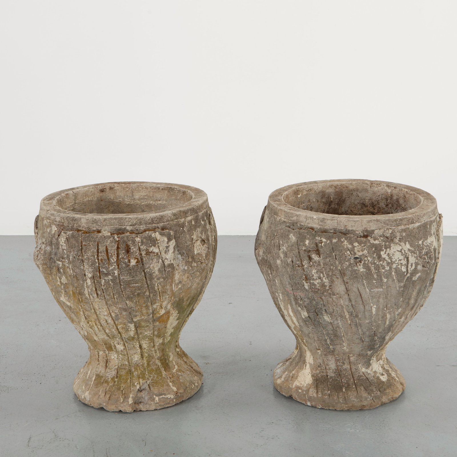 Pair of Carved Stone Garden Urn Planters, 1960s: Pair of sculptural stone planters featuring a rounded bowl form resting on a tapered pedestal base. The textured surfaces display a naturally aged patina acquired through outdoor exposure. Elegant gar