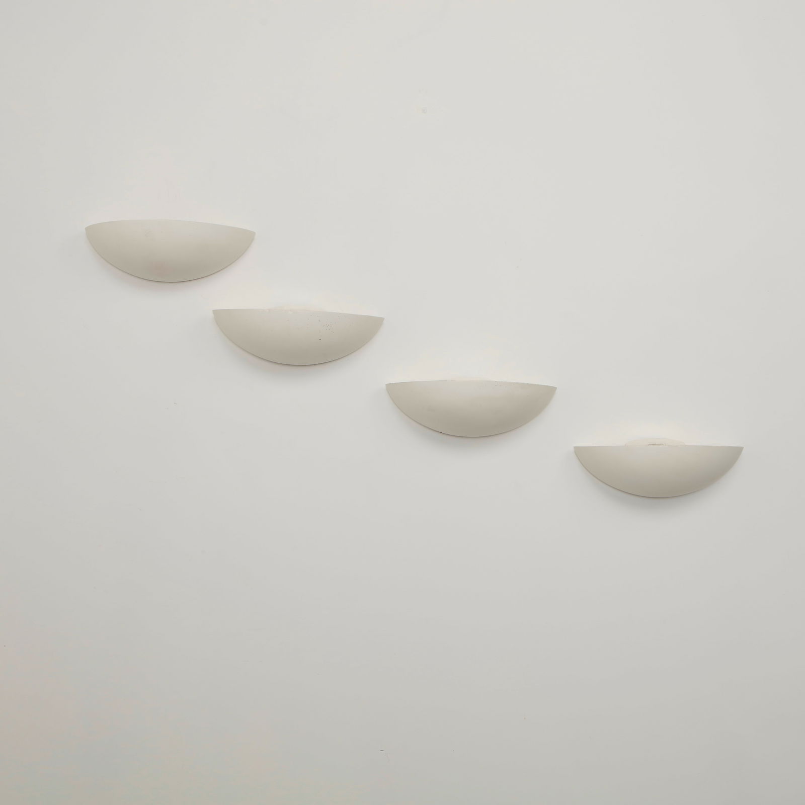 SCE, Set of Four Ceramic Wall Sconces, 1980s: Elegant half moon wall sconces executed in white ceramic with softly curved profiles that diffuse light upward and outward. Their restrained geometric form reflects the clean architectural language of