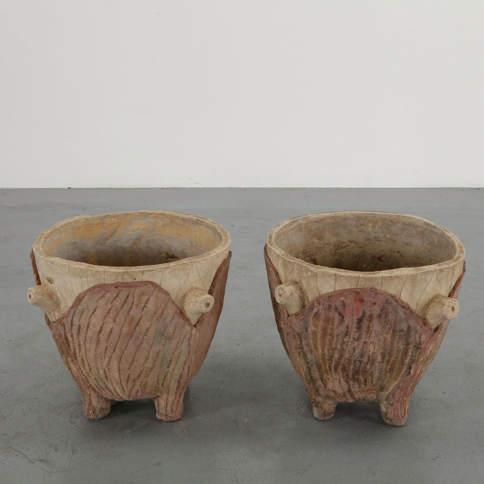 Pair of Italian Faux Bois Planters, 1960s: Executed in sculpted concrete with textured shell motifs and naturalistic faux bois detailing, this pair of planters presents a sculptural garden presence. The aged surface and hand finished character