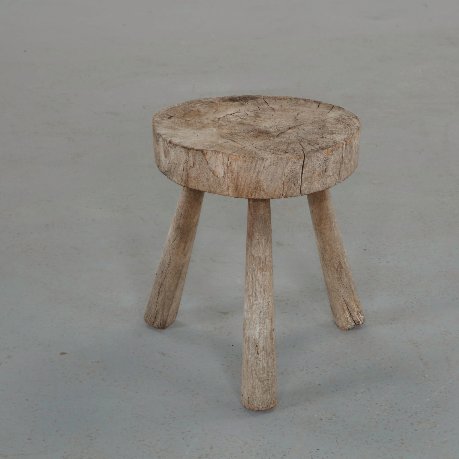 Brutalist Solid Wood Round Stool, Europe, 1960s: Crafted from a thick circular slab of solid wood resting on three splayed legs. The expressive grain, weathered surface, and visible cracking reveal the material in its raw state. A compact sculptural