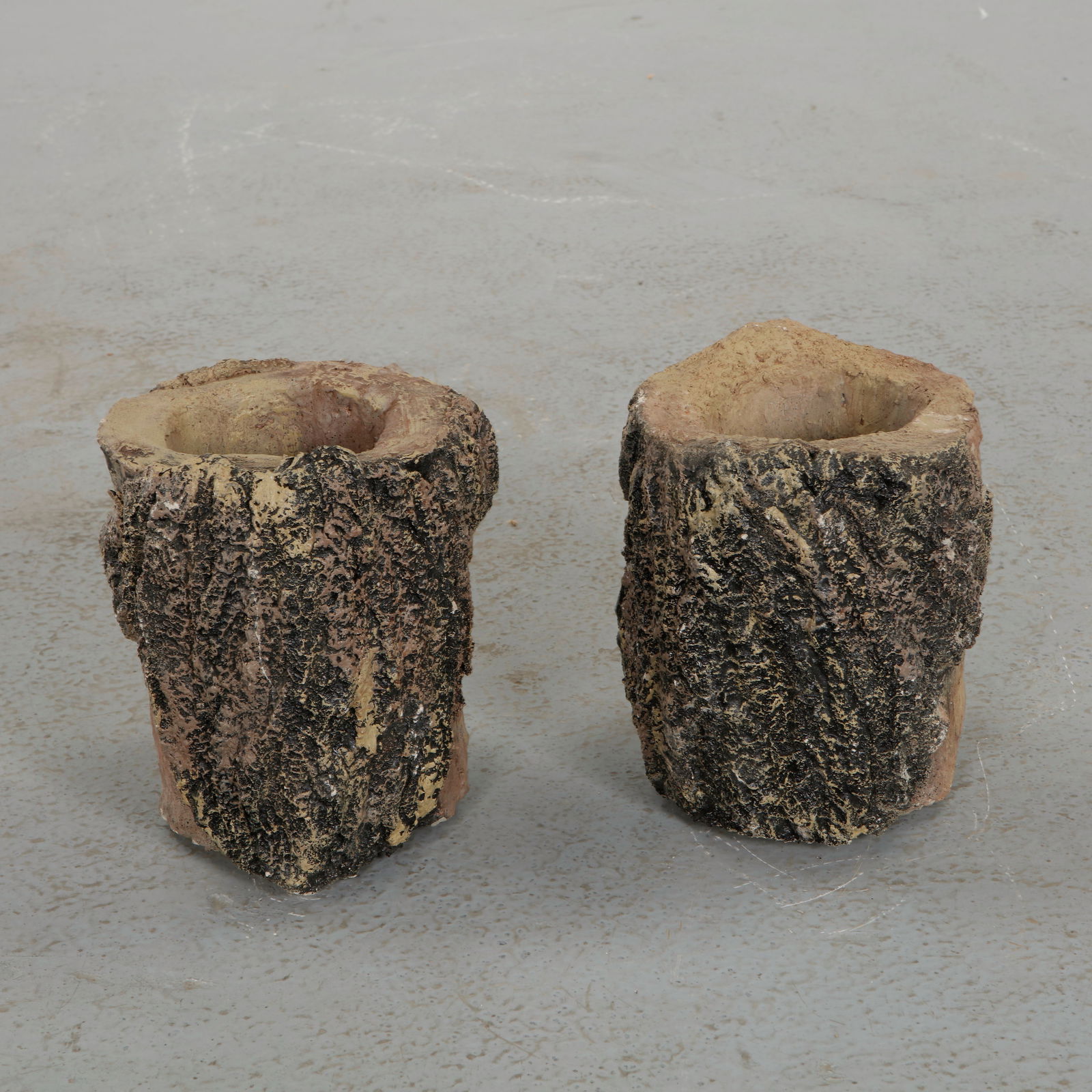 Pair of Round Faux Bois Planters, 1960s: Pair of sculptural planters modeled in textured faux bois imitating the irregular surface of tree bark. The organic cylindrical form and hand worked surface evoke rustic garden traditions while