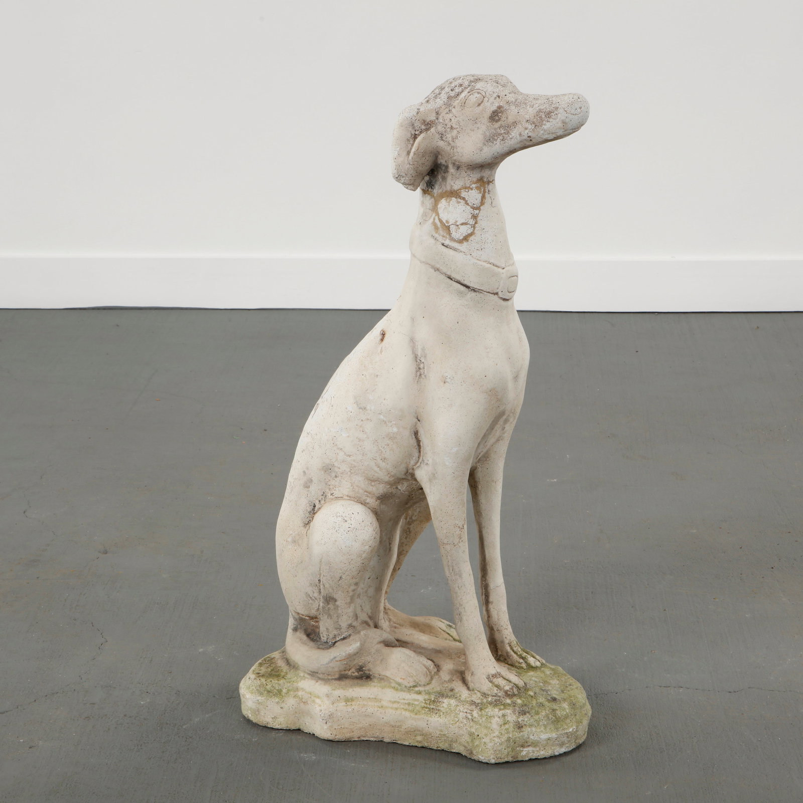 Cast Stone Greyhound Garden Sculpture, Europe, 1950s: Elegant cast stone sculpture depicting a seated greyhound with elongated proportions. Executed with restrained naturalism and softened contours, enhanced by an aged patina. A poetic garden figure evoc