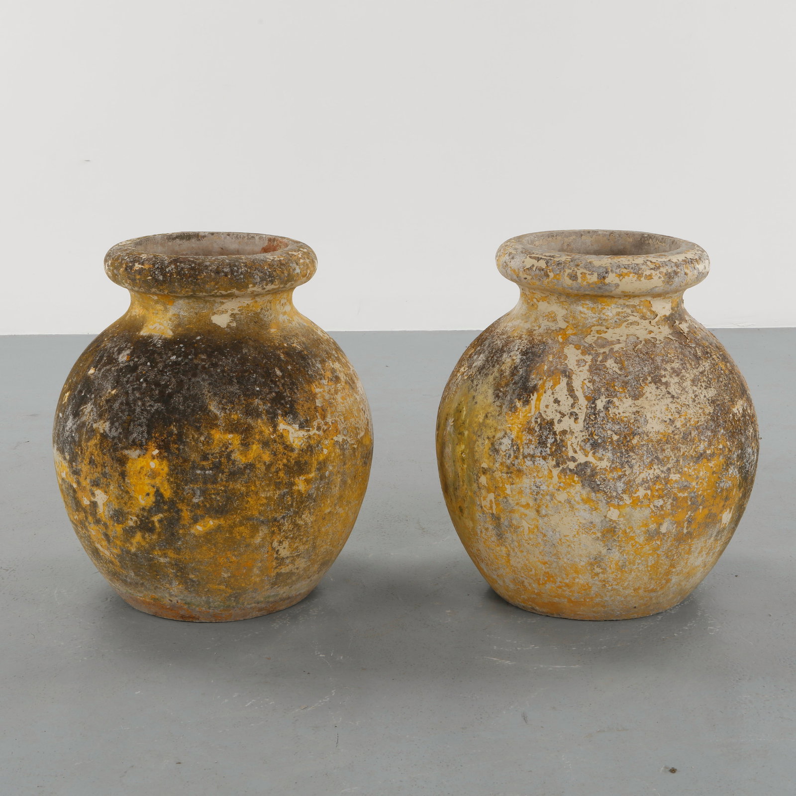 Willy Guhl, Pair of Large Concrete Jar Planters, 1960s: Crafted in cast concrete with a generous rounded body and wide collar rim, these vessels bears a richly weathered surface with lichen and patina from decades of outdoor use. A rare oversized example o
