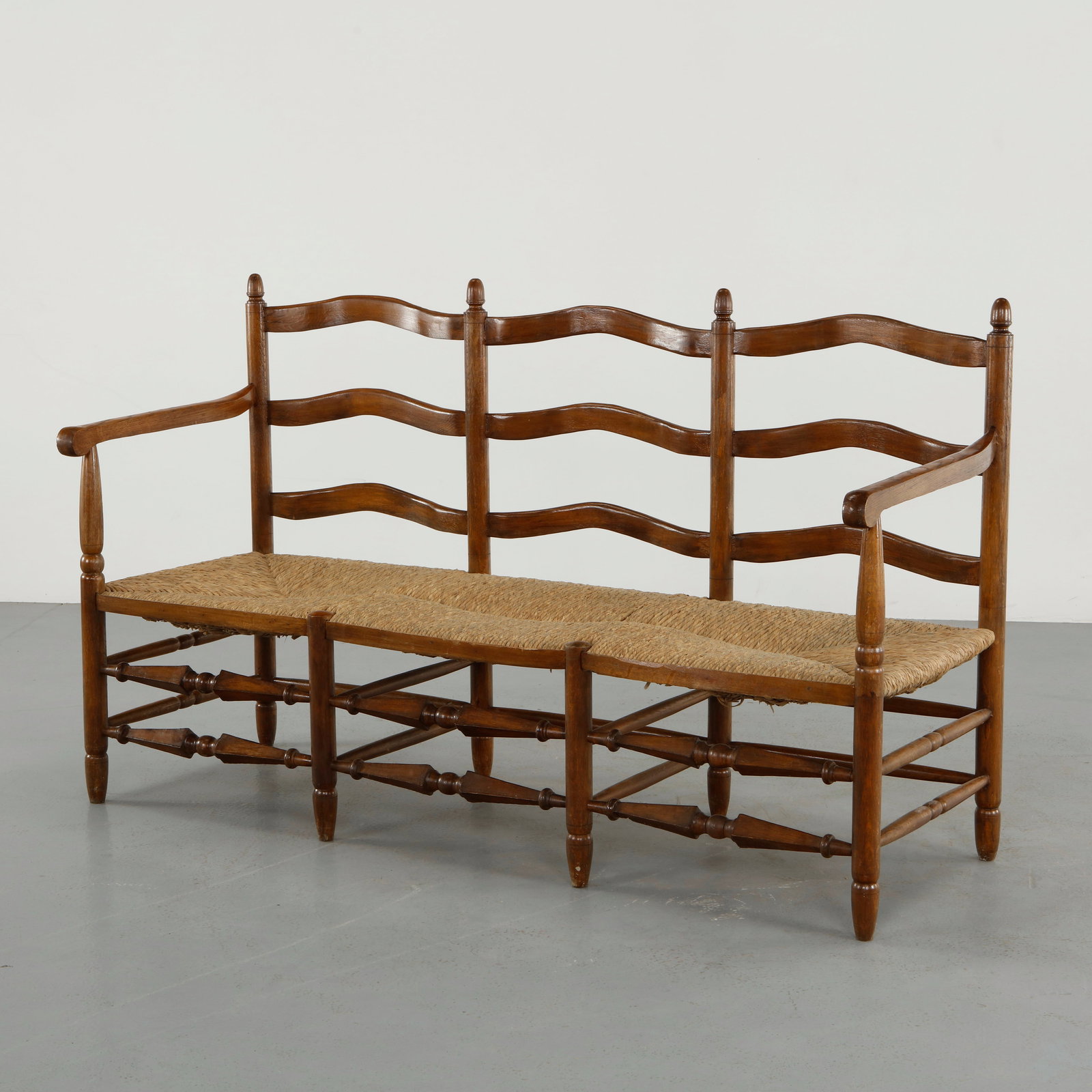 French Provincial Brutalist Wood and Rope Bench, 1960s: A long bench crafted in solid wood with a handwoven rope seat, featuring a distinctive triple backrest with gently undulating slats. The turned supports and stretcher base demonstrate fine traditional
