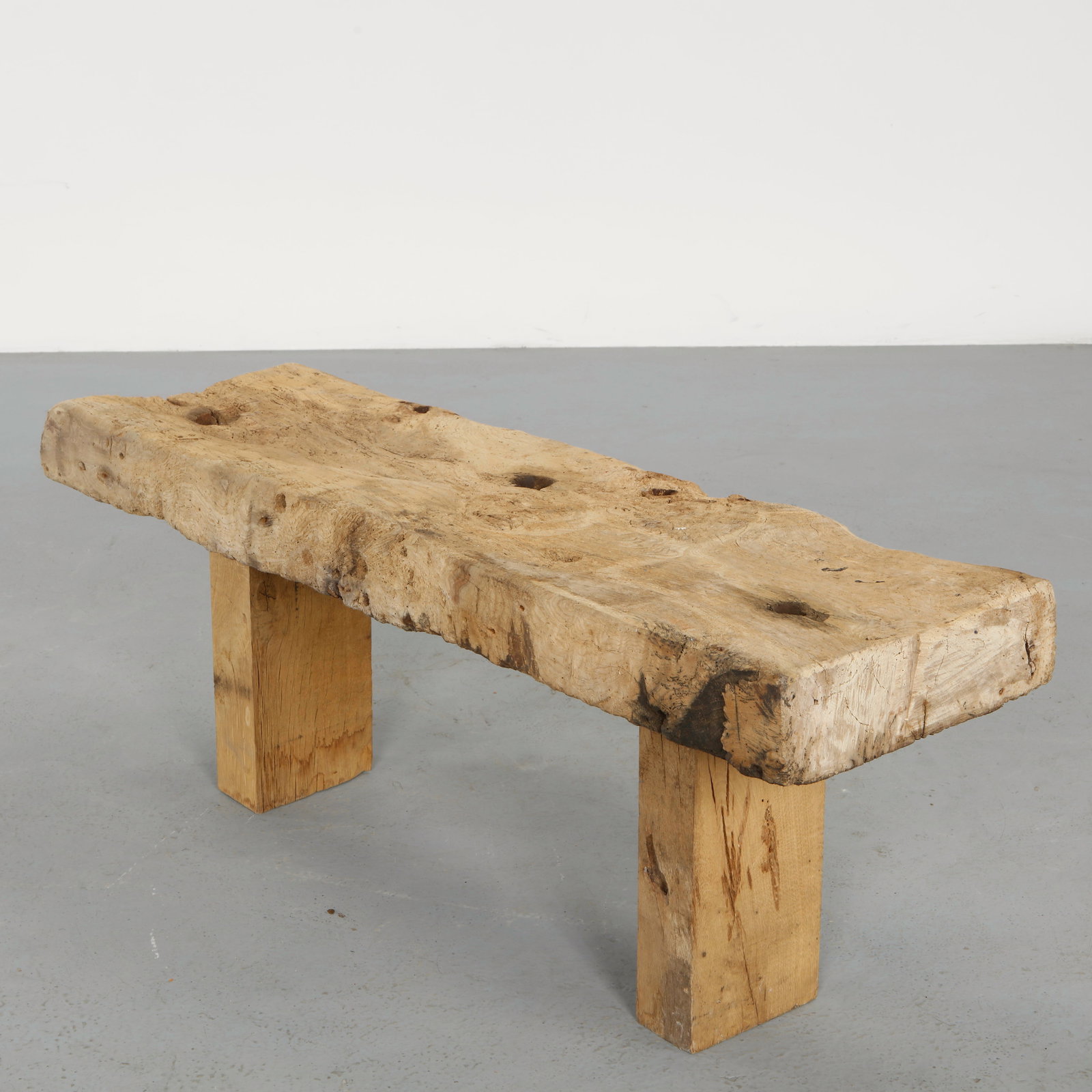 Brutalist Solid Wood Bench in the Style of Nakashima, 1960s: A sculptural bench carved from a thick slab of wood, retaining its natural edges and organic irregularities. The massive supports emphasize a raw and expressive approach to material. Height: 19.5 in.