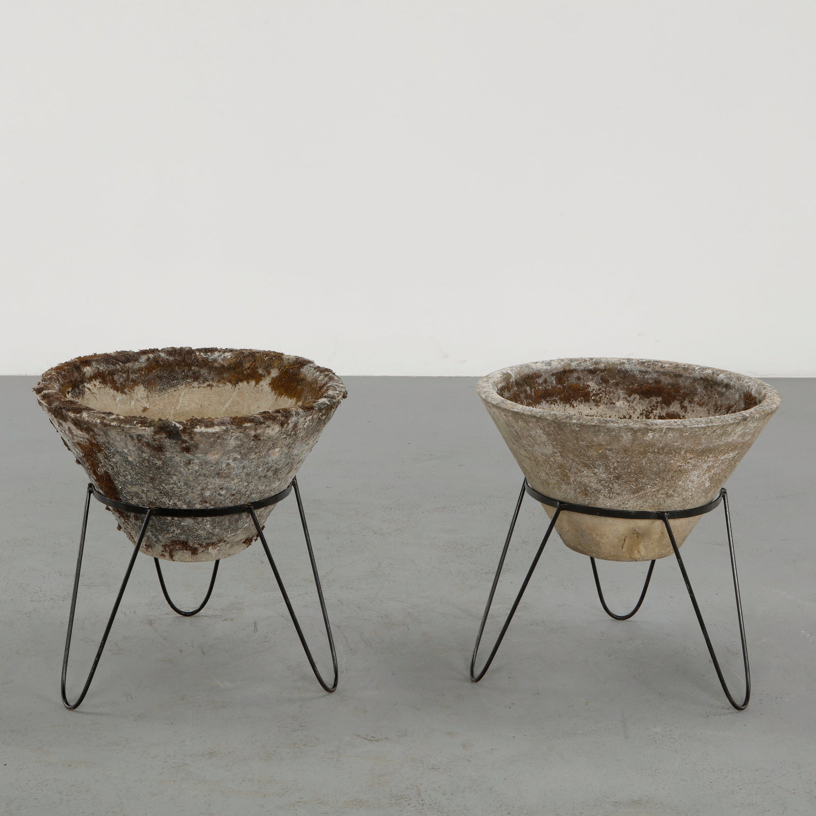Willy Guhl, Pair of Conical Planters, 1960s: Iconic Willy Guhl silhouettes in compact form, these conical planters rest atop minimalistic metal stands, weathered yet timeless. Height: 21.5 in. Diameter: 21.75 in.Â