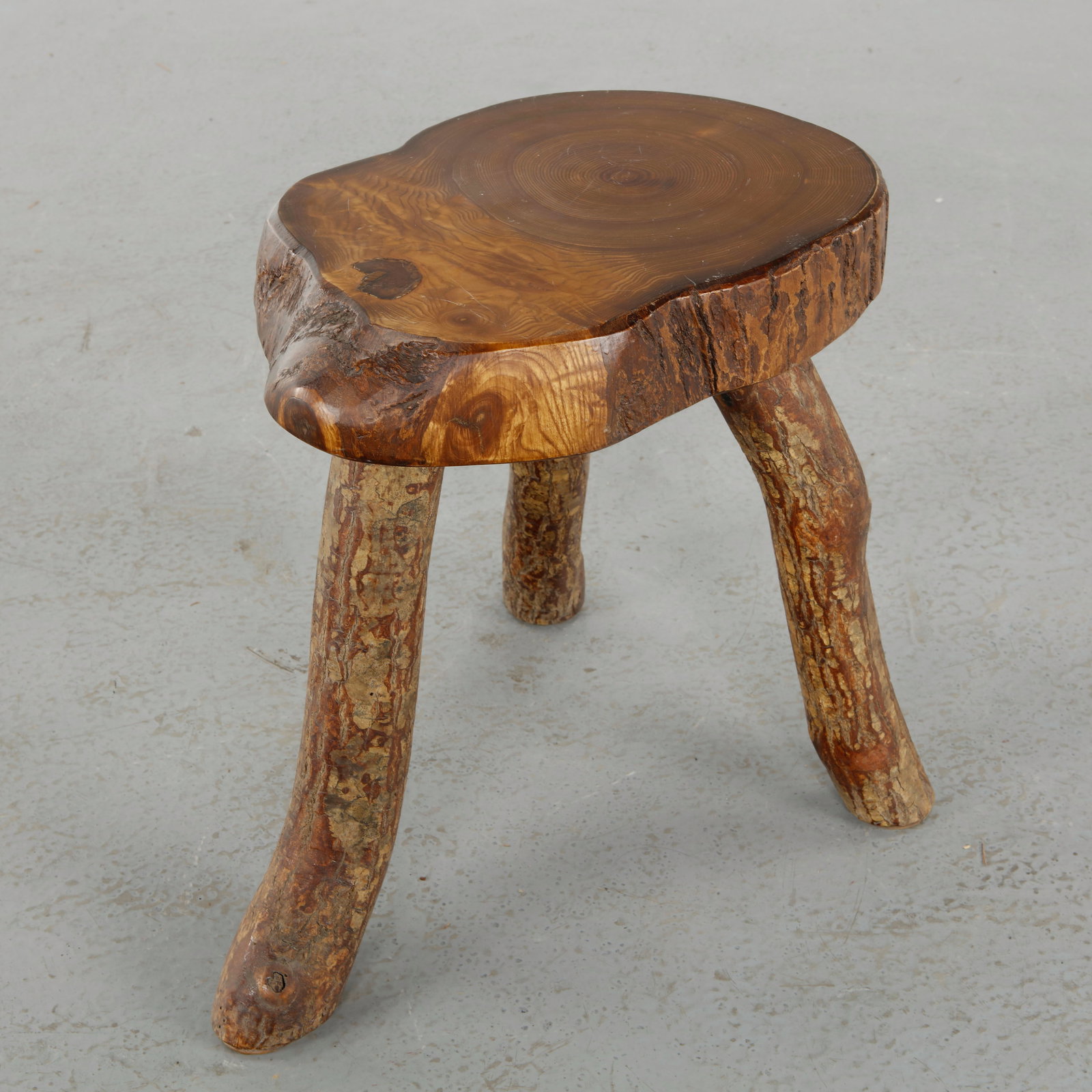 Brutalist Tripod Stool, 1960s: Sculptural tripod stool carved from solid wood, showcasing irregular contours and a naturalistic approach to design. The patina enhances its rustic and authentic character. Height: 16 in. Width: 15 in