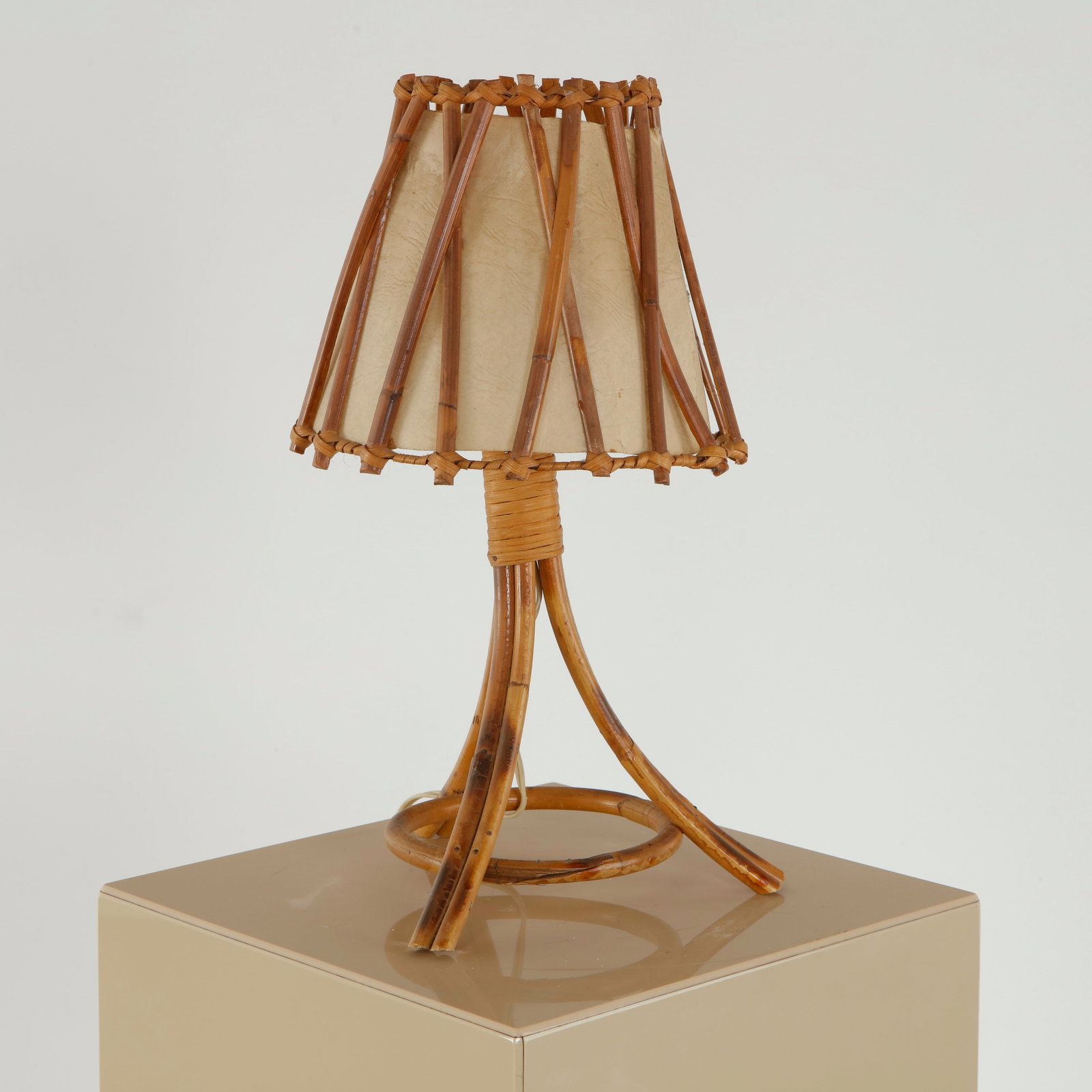 Louis Sognot, Table Lamp, 1960s: Table lamp in rattan featuring a tripod base and a woven shade with geometric rhythm. The piece reflects a warm materiality and careful hand-crafted assembly. Height: 15.5 in. Diameter: 8 in.
