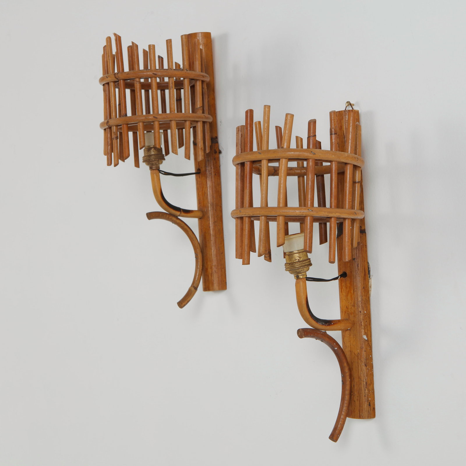 Louis Sognot, Pair of Rattan Sconces, 1960s: Wall lights in carved and assembled rattan with cylindrical shades framed by vertical elements. Their architectural composition brings texture and depth to interior spaces. Height: 12.5 in. Diameter: