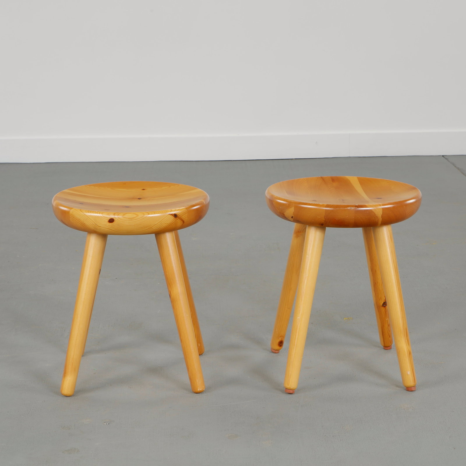 Pair of French Pine Stools in the style of Charlotte Perriand, 1960s: Crafted in solid pine with softly rounded seats and tapered legs, these stools evoke the alpine modernist vocabulary associated with Perriand work. Simple construction and warm patina underline their