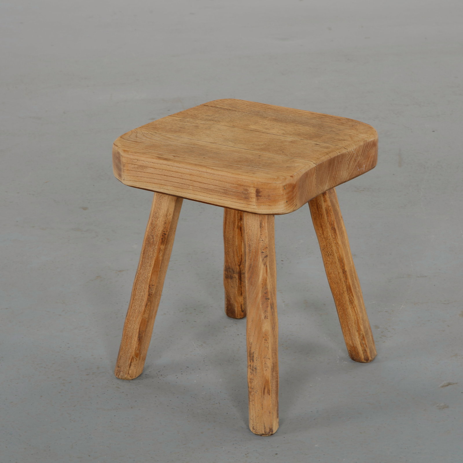 Brutalist Tripod Stool in the Spirit of Charlotte Perriand, France, 1960s: Solid wood stool featuring a thick organically shaped seat supported by four robust legs. The expressive carving and raw material presence recall the rustic alpine aesthetic associated with French mod