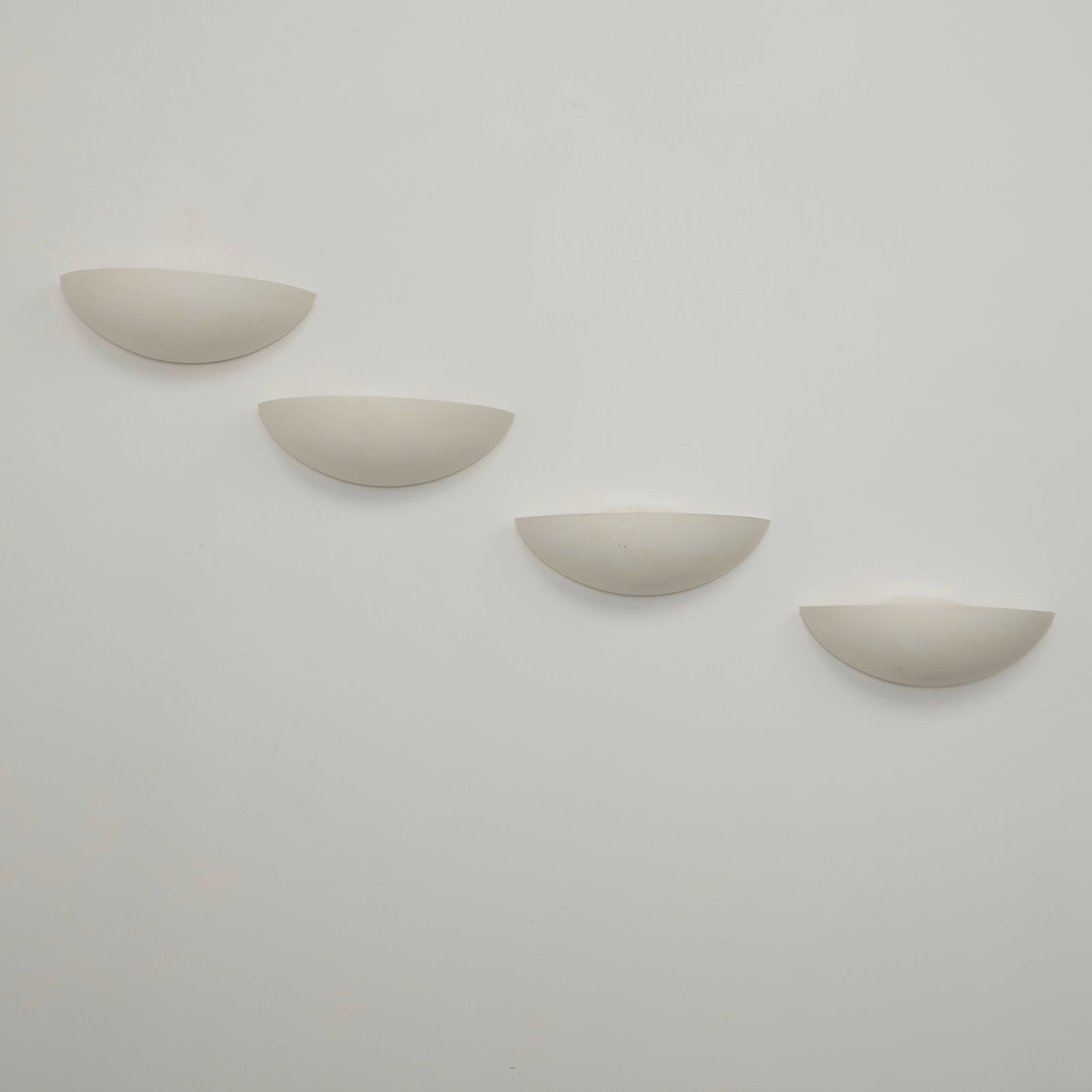 SCE, Set of Four Ceramic Wall Sconces, 1980s: Elegant half moon wall sconces executed in white ceramic with softly curved profiles that diffuse light upward and outward. Their restrained geometric form reflects the clean architectural language of