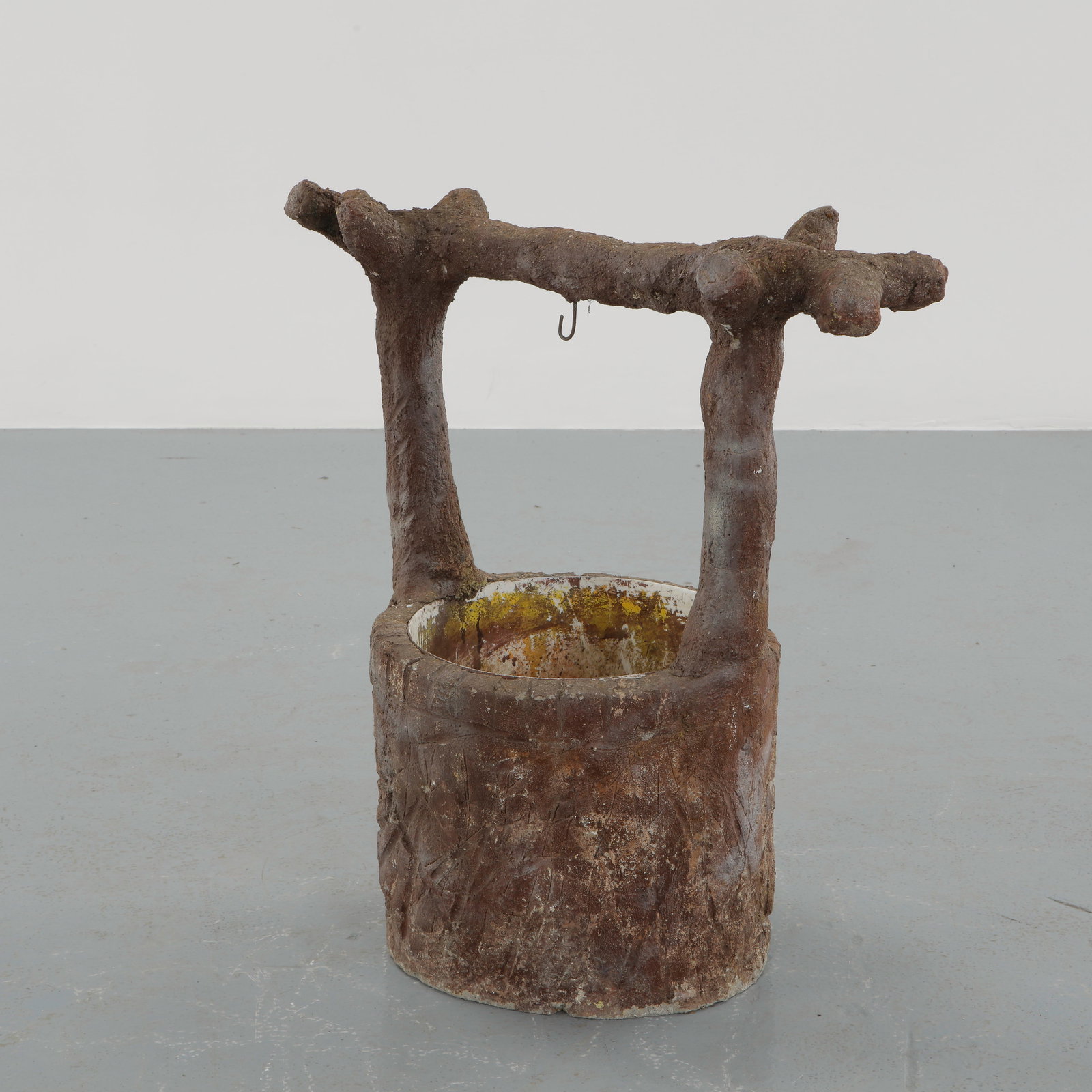 Faux Bois Concrete Well Planter, 1960s: Executed in sculpted concrete with a richly textured faux bois surface, this planter takes the form of a primitive well supported by organic uprights. The expressive patina and hand worked relief