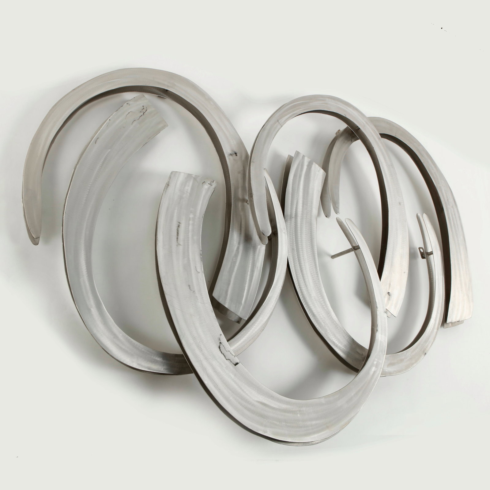 Artisant Crafted Metal Sculputre, Signed, 1970s: Handcrafted metal sculpture composed of interlocking curved elements with a brushed finish. The rhythmic interplay of forms conveys movement and reflects the experimental spirit of 1970s design.