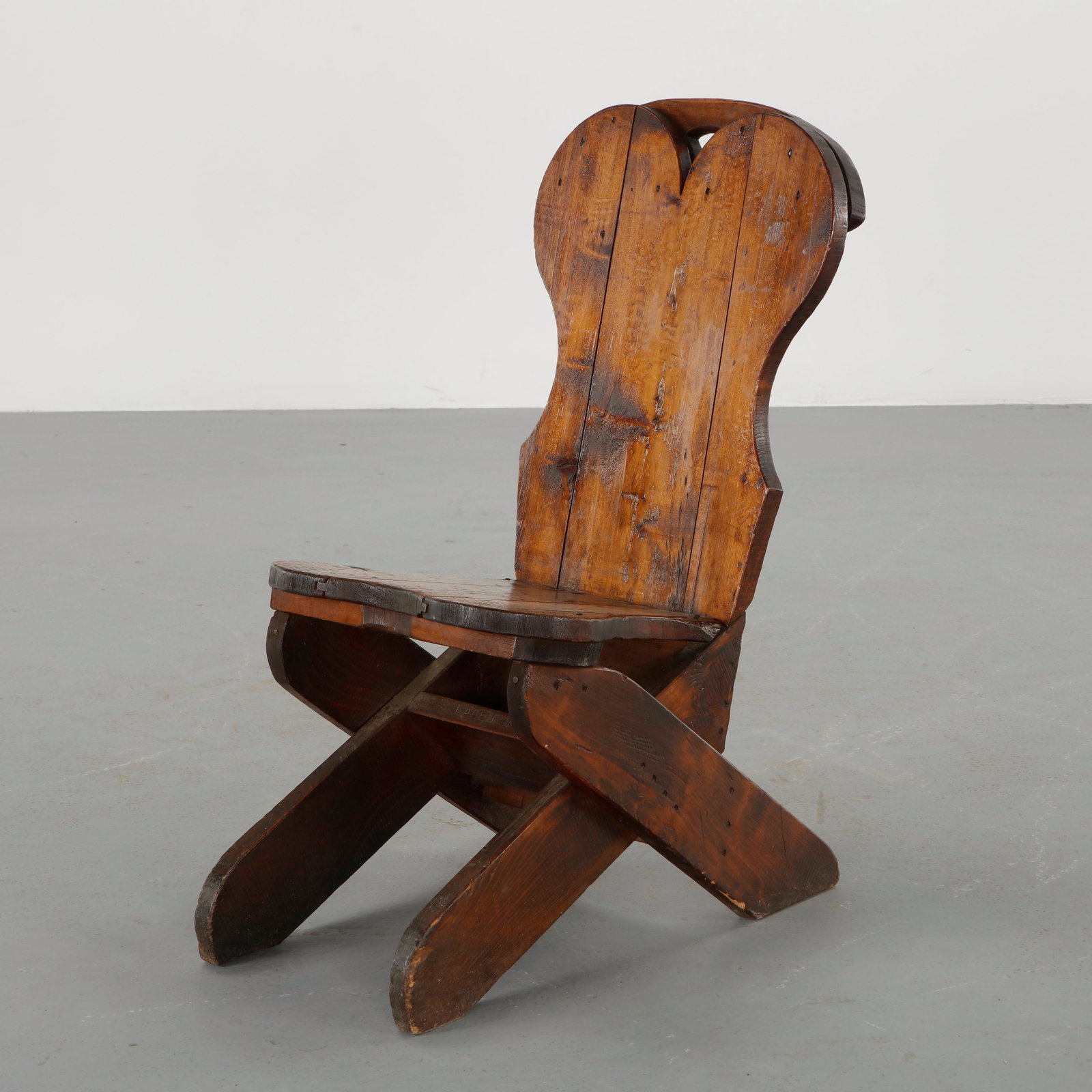 Brutalist Wood Chair, 1960s: Executed in thick solid wood with sculptural carved seat and distinctive crossed plank base. The expressive grain and visible joinery emphasize the raw materiality of the design. A striking brutalist