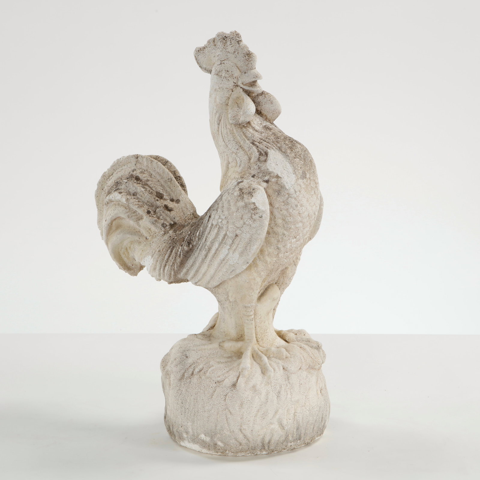 Rooster Stone Sculpture, 1950s: Stone rooster sculpture executed with stylized plumage and strong vertical stance. A charming decorative accent with weathered patina, evoking traditional European garden ornamentation. Height: 22 in.