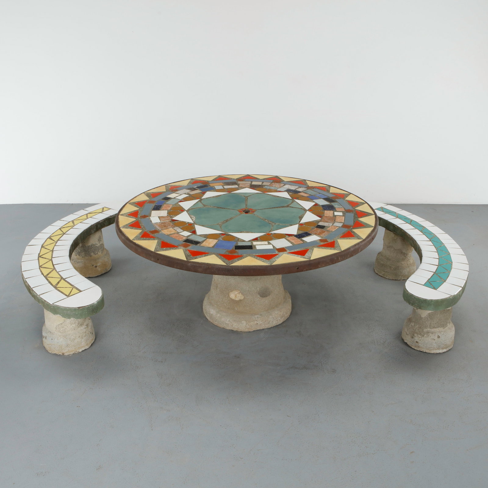 Monumental Multicolor Mosaic Dining Set, France, 1960s: Monumental garden table executed in concrete with an elaborate hand laid mosaic top, accompanied by a pair of curved benches featuring complementary tile work. The composition combines architectural s