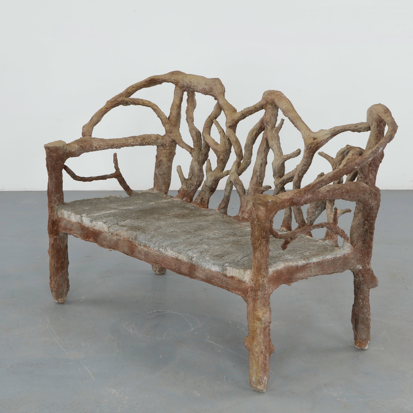 Rustic Faux Bois Garden Bench: A straight garden bench executed in faux bois concrete, the seat molded to simulate timber planks with finely incised grain. The openwork back and arms are formed from intertwined branch motifs, lendi