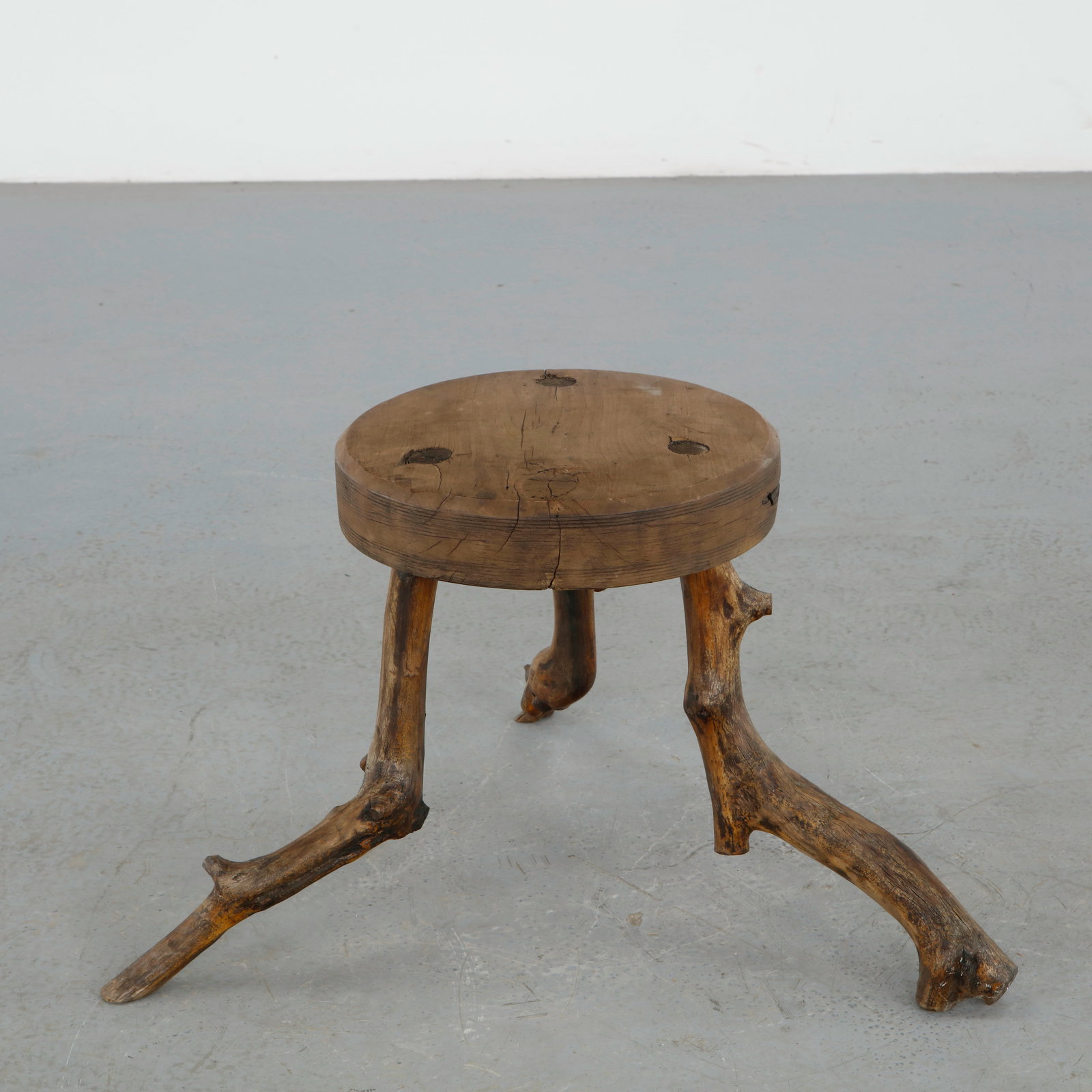 Brutalist Vine Wood Stool, 1960s: Rustic Brutalist stool executed from solid wood with naturally formed vine branch legs and a thick circular seat displaying expressive knots and organic fissures. The sculptural silhouette reflects th