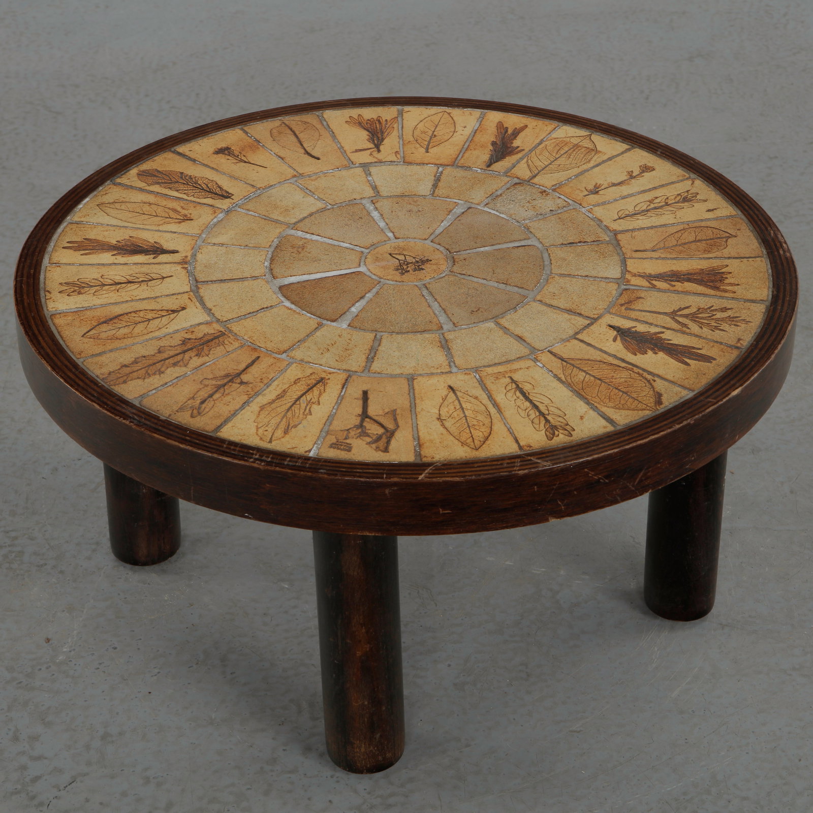 Roger Capron, Rare Small Ceramic Round Coffee Table, Stamped, 1960s: Very rare small circular coffee table with a ceramic tile top decorated in a radial composition of stylized natural motifs, framed by a solid wood surround and resting on a sculptural wooden base. A r