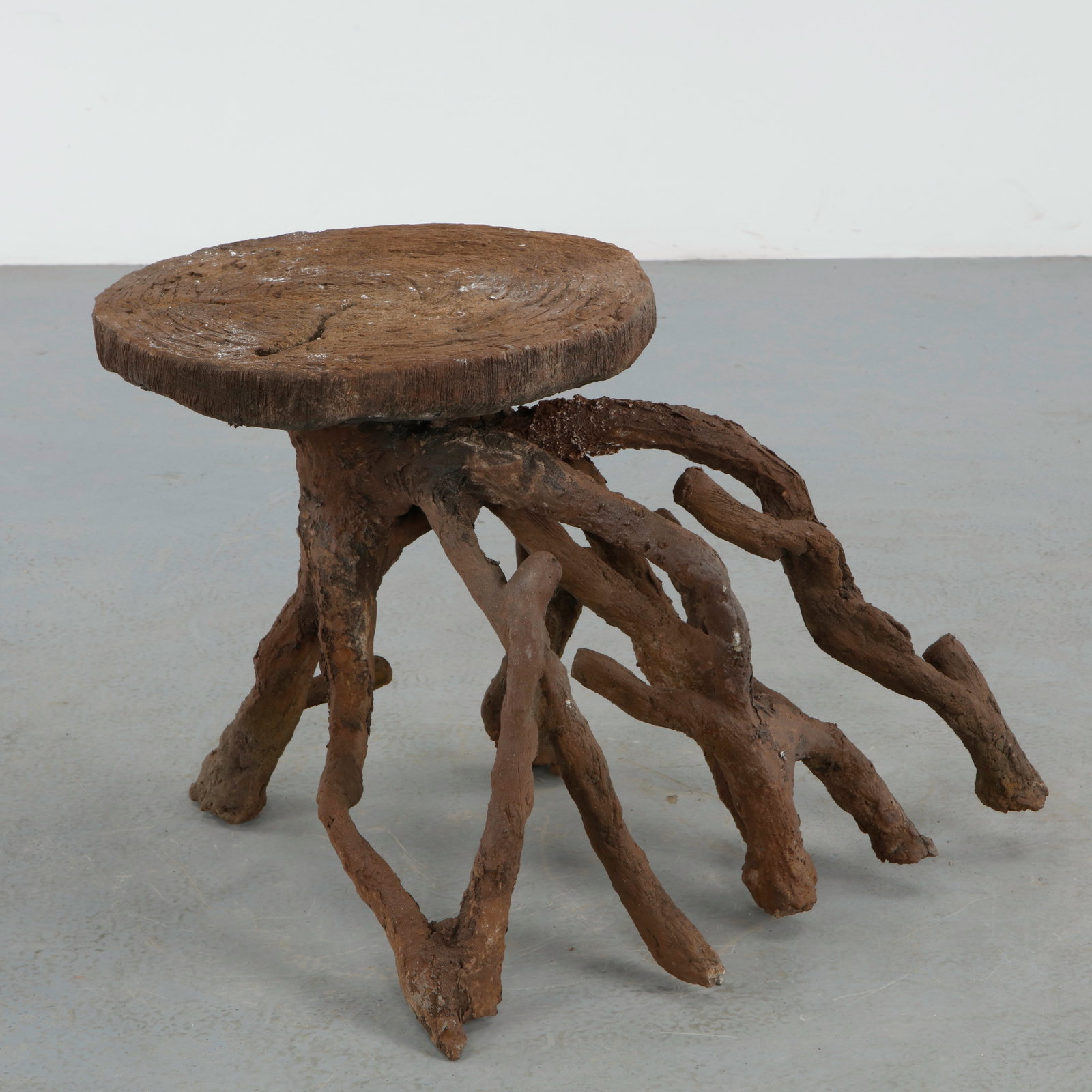 Sculptural Faux Bois Coffee Table: Sculptural faux bois coffee table featuring an organic root form base supporting a circular top carved with simulated wood grain. The expressive handcrafted construction evokes the romantic naturalism