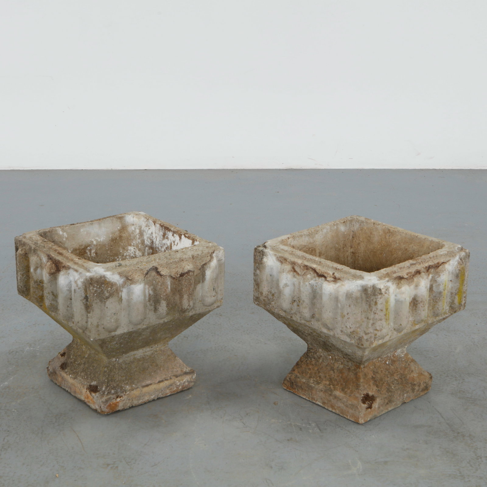 Pair of Square Stone Planters, 1960s: A robust pair of carved stone planters featuring clean square forms and thick walls. The surfaces display a naturally weathered patina, enhancing their sculptural presence. Ideal for architectural gar