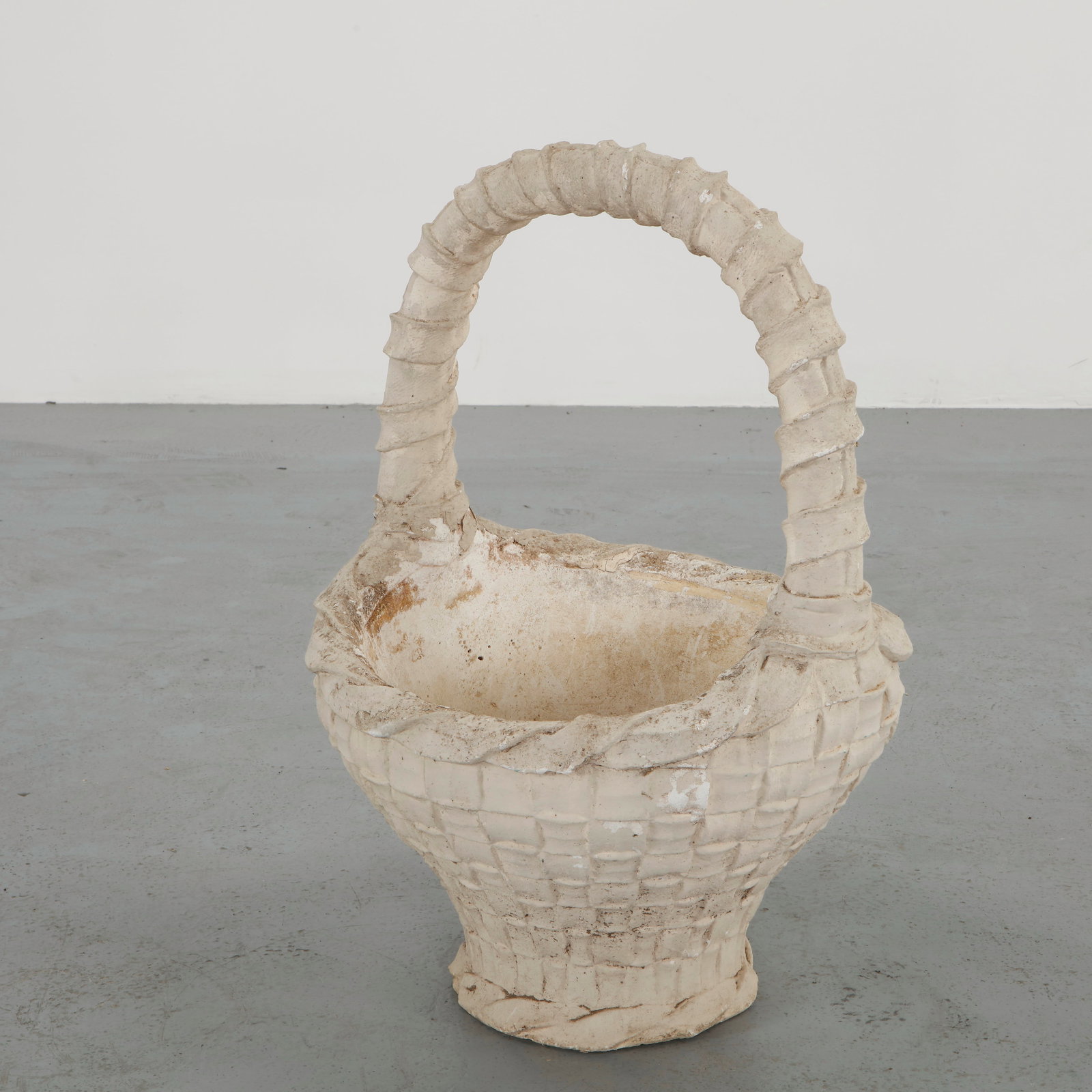 Concrete Basket Planter, 1960s: Cast concrete planter shaped as a woven basket with an elegant arched handle. The carefully modeled texture evokes traditional basketry translated into durable outdoor material. A poetic garden