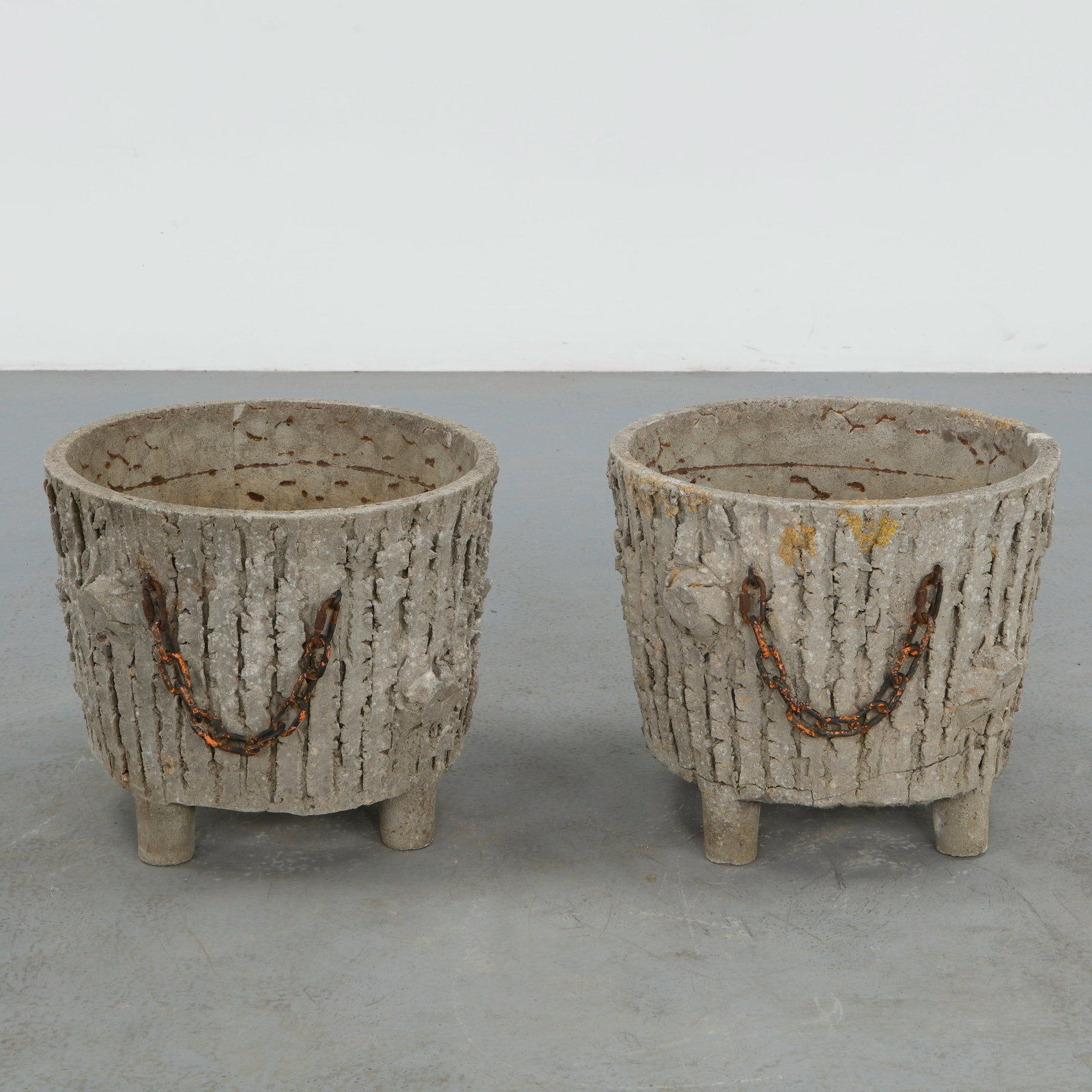 Faux Bois Pair of Round Planters with Chains: Pair of round faux bois concrete planters featuring deeply textured bark like surfaces accented by suspended iron chain handles. The rustic sculptural forms embody the enduring charm of midcentury