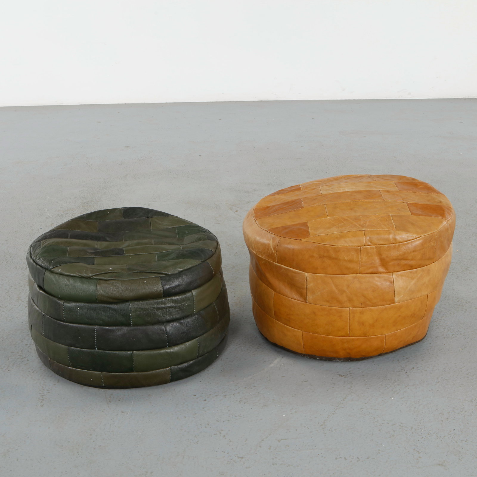 De Sede, Pair of Leather Ottomans, 1960s: Executed in hand-stitched patchwork leather, these sculptural ottomans exemplify De Sede signature craftsmanship and supple upholstery. Their green and camel tones and generous forms invite both comfo