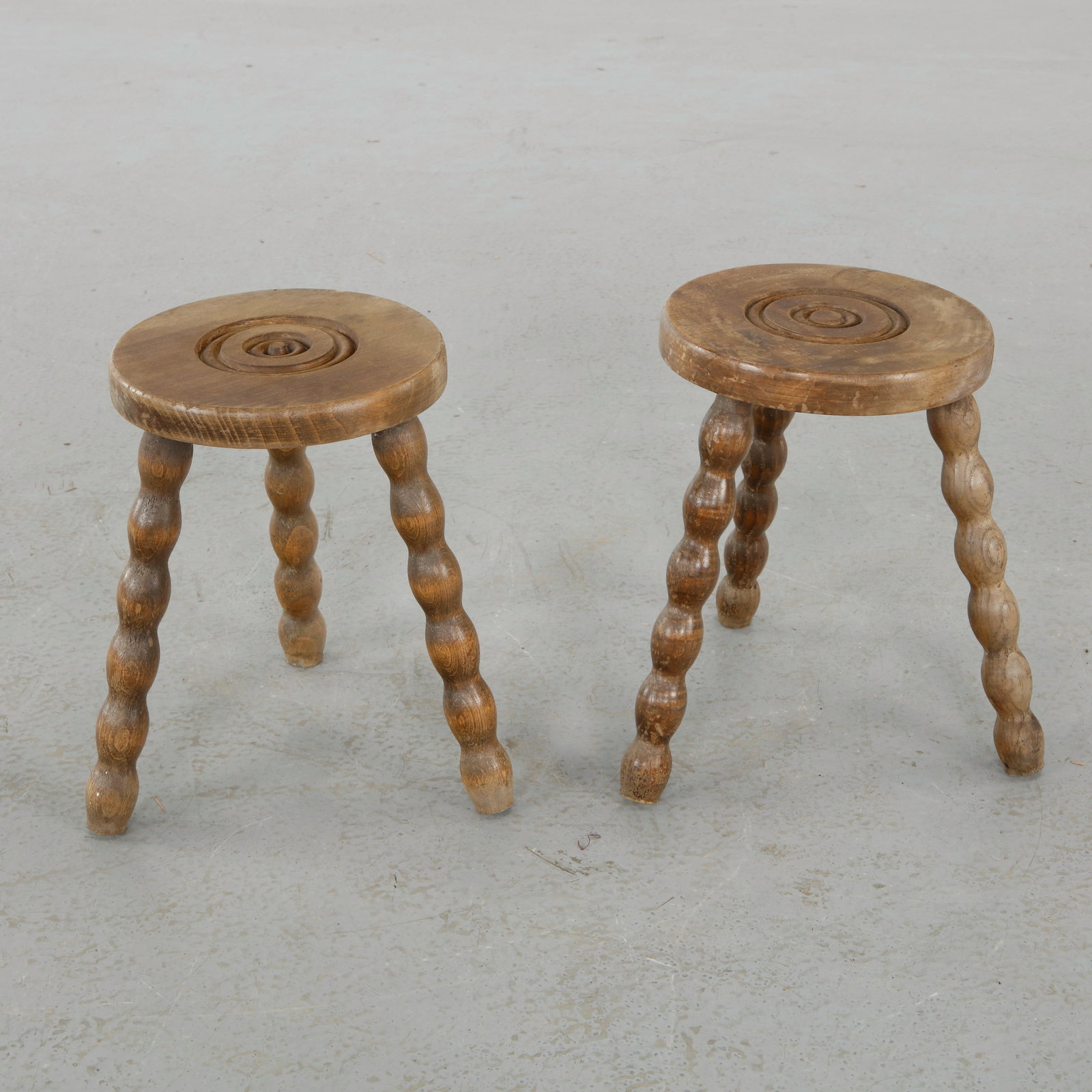 Charles Dudouyt, Pair of Brutalist Wood Stools, 1960s: Pair of stools in solid wood with turned legs and deeply carved seats, embodying Dudouyt bold sculptural language. A striking and cohesive duo with strong decorative presence. Height: 13 in. Diameter: