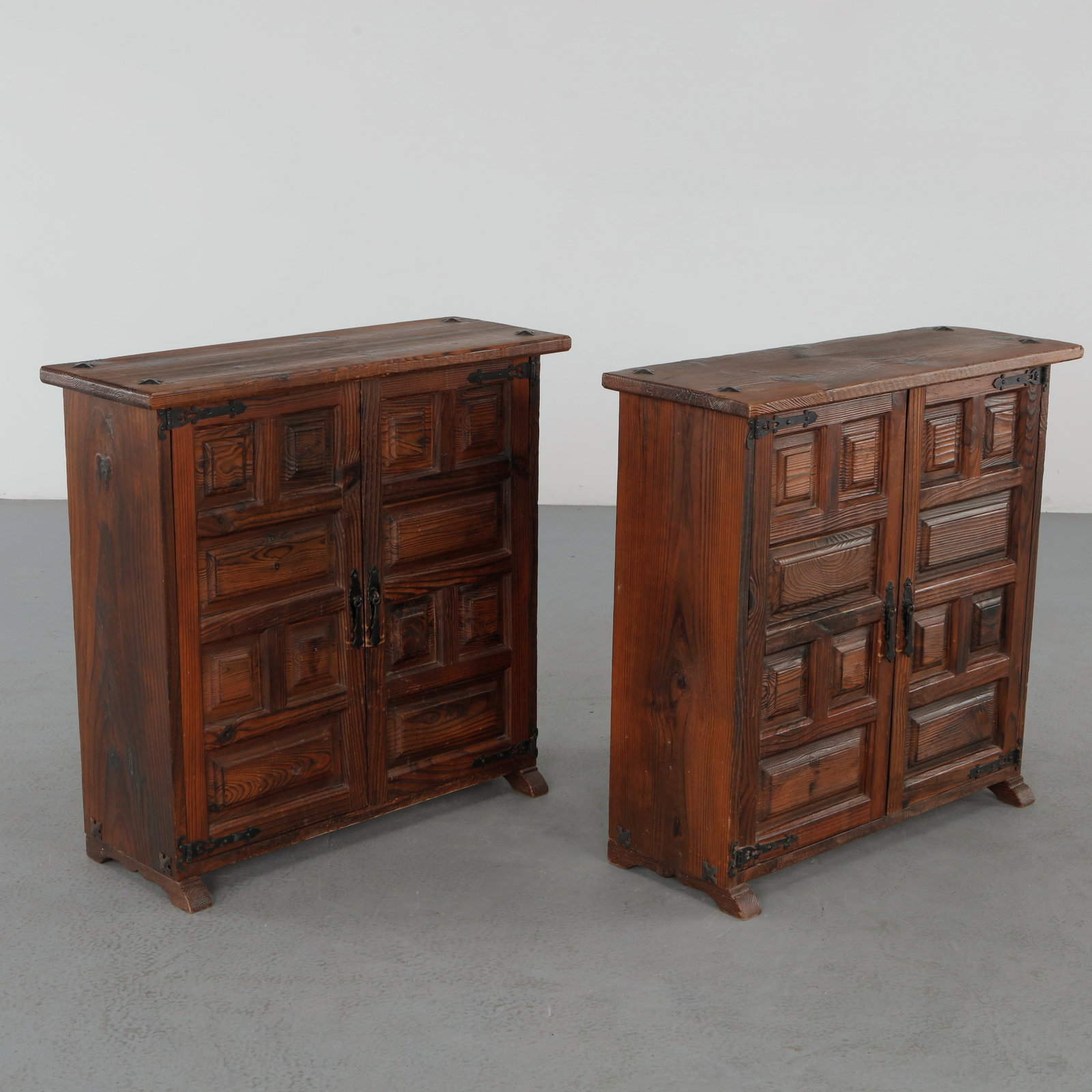Pair of 19th-Century Spanish Catalan Baroque Carved Walnut Cabinets: Rare pair of Spanish Catalan cabinets executed in richly grained walnut, featuring deeply carved geometric panel doors and hand forged iron hardware. The architectural silhouettes and substantial craf