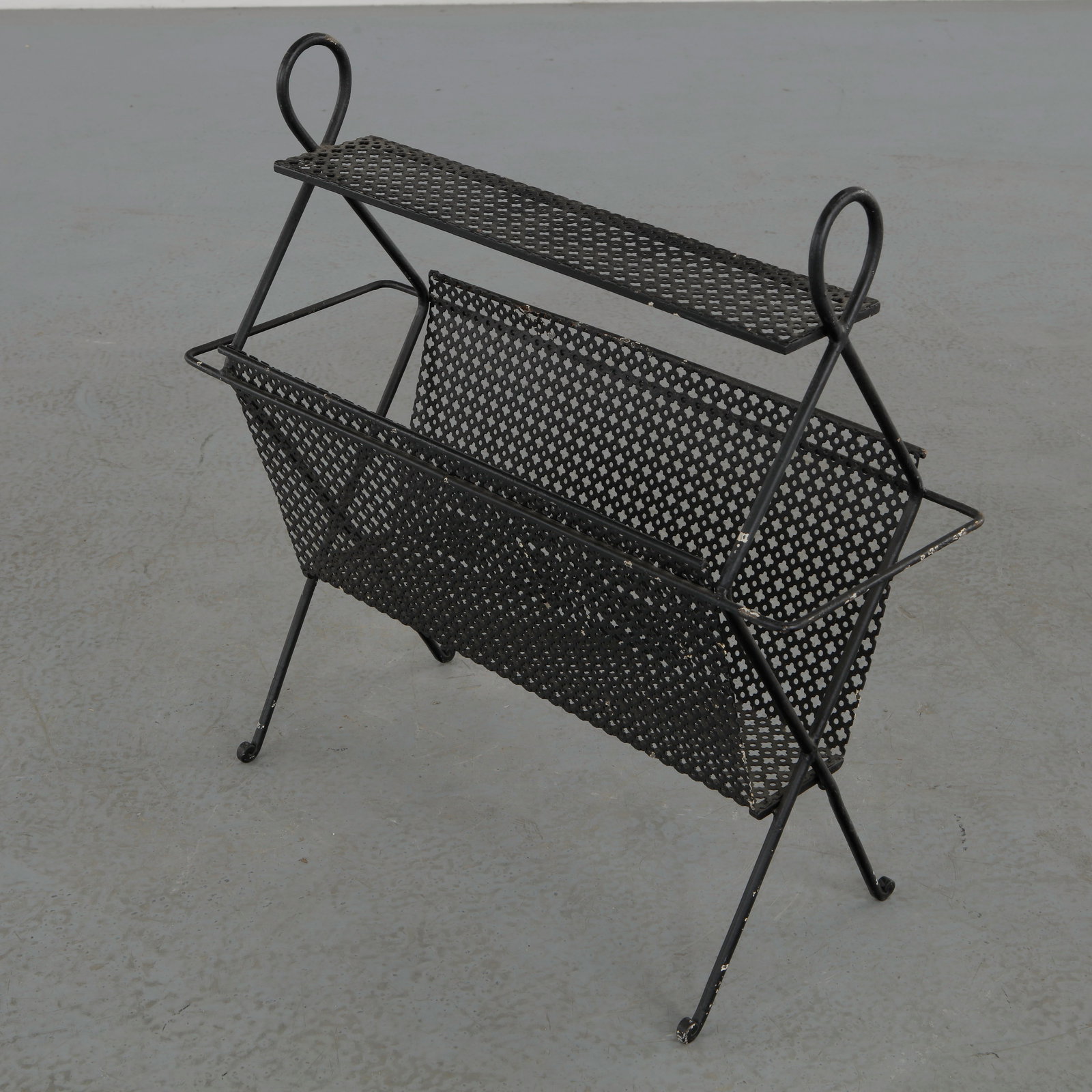 Mathieu Mategot, Perforated Black Metal Magazine Rack, 1950s: A refined magazine rack crafted in perforated metal with a delicately folded structure. The airy construction and graphic lines evoke the work of Mathieu Mategot. A functional yet sculptural piece cha