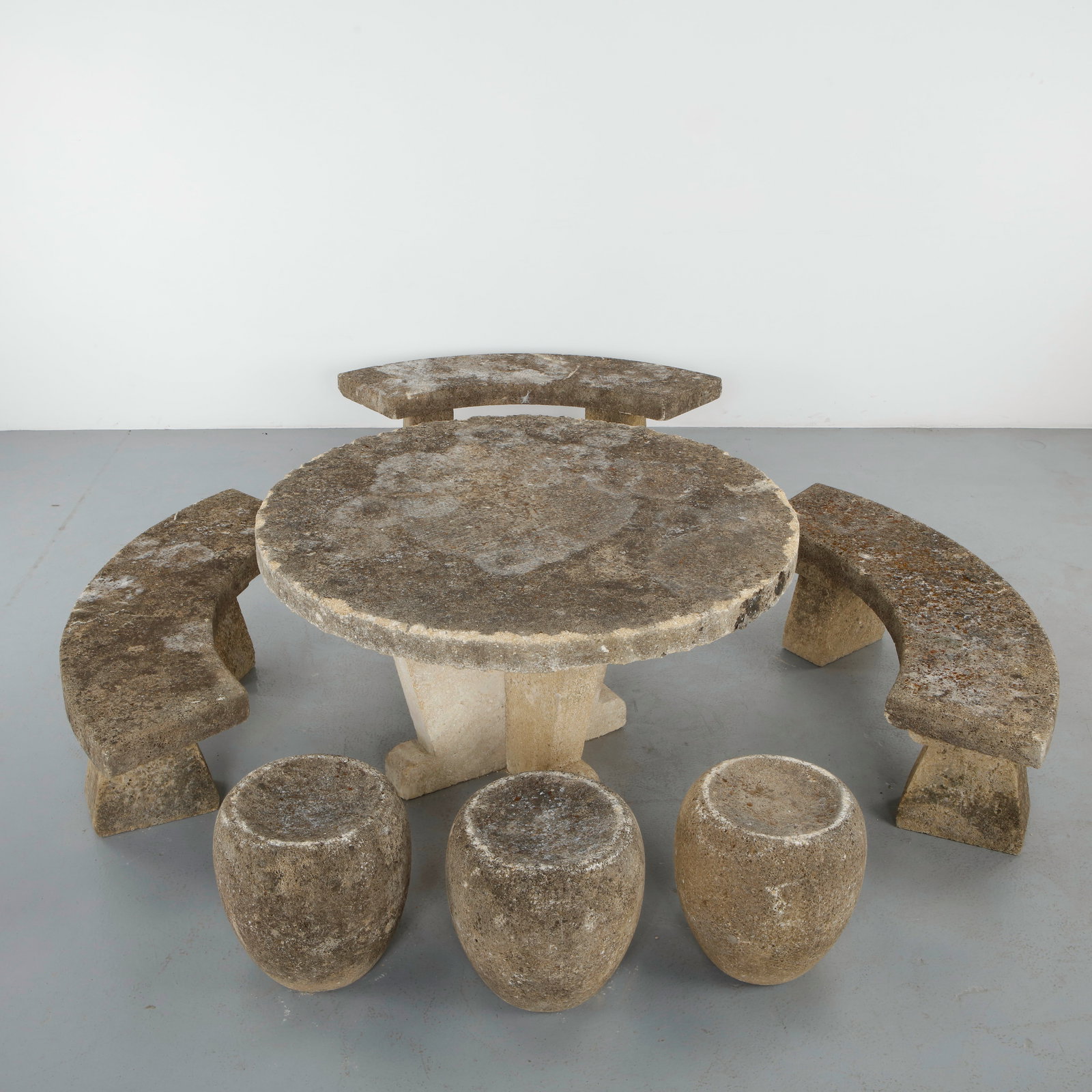 Limestone Garden Dining Set with Benches and Stools, France, 1960s: Rare sculptural garden dining set executed in carved limestone, comprising a circular table and three curved benches. The ensemble features heavily weathered surfaces with a naturally eroded texture a
