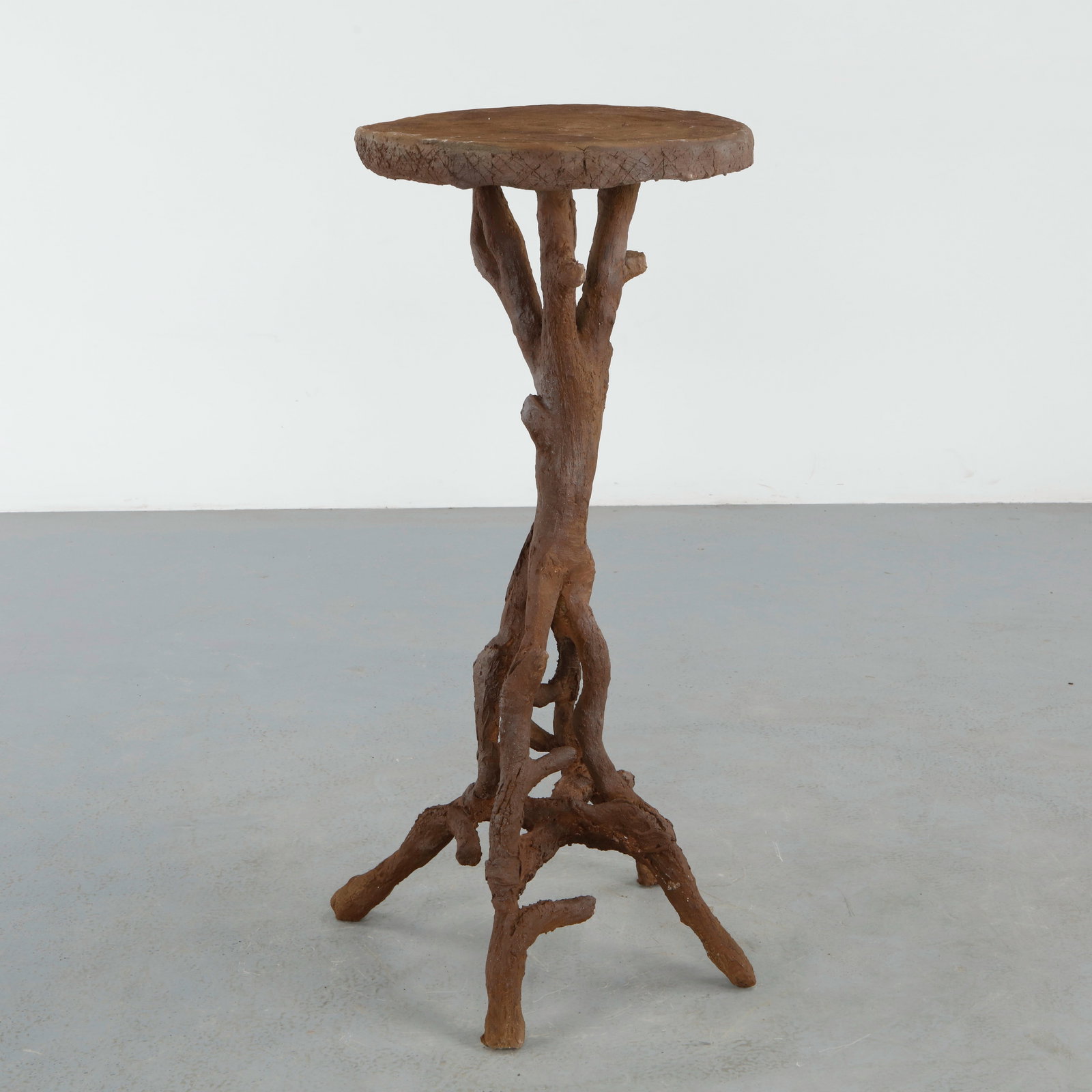 Sculptural Faux Bois Pedestal: Sculptural faux bois pedestal raised on intertwined root form supports beneath a circular top carved with naturalistic wood grain detail. The expressive handcrafted form gives the piece a striking org