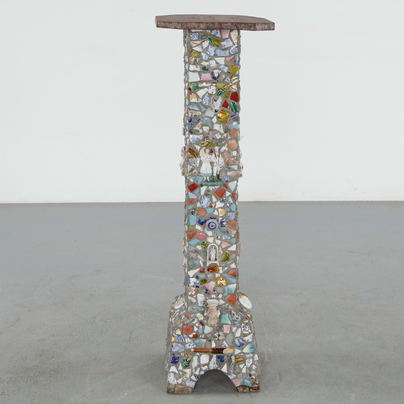 Folk Art Trencadis Pedestal Table, 1960s: Whimsical sculptural pedestal table executed in cement and richly embedded with porcelain fragments, colored glass, and miniature figurative elements. The surface composition recalls the poetic assemb