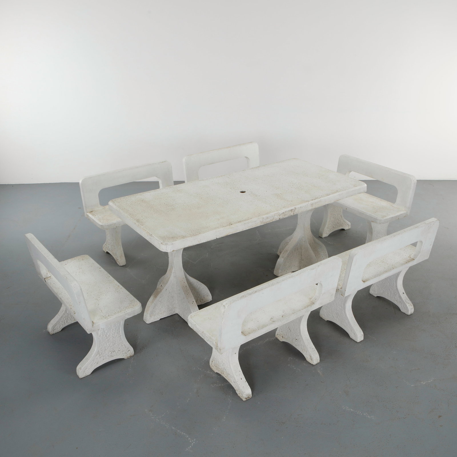Terrazzo Garden Dining Set with Six Benches, 1970s: Monumental outdoor dining ensemble executed in white terrazzo, comprising a rectangular dining table and six independent benches with sculptural openwork backrests. The set features softly textured su